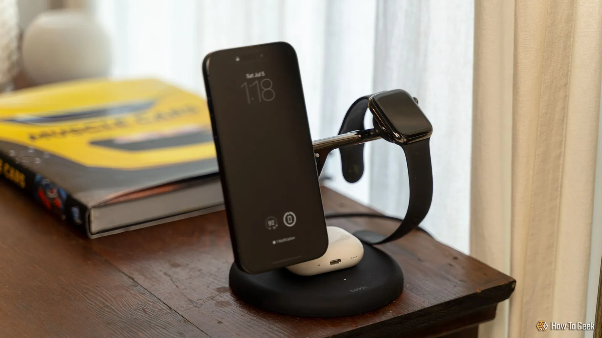 Bộ sạc Belkin BoostCharge Pro 3-in-1 đang sạc đồng thời iPhone, Apple Watch và AirPods trên bàn gỗ gọn gàng
