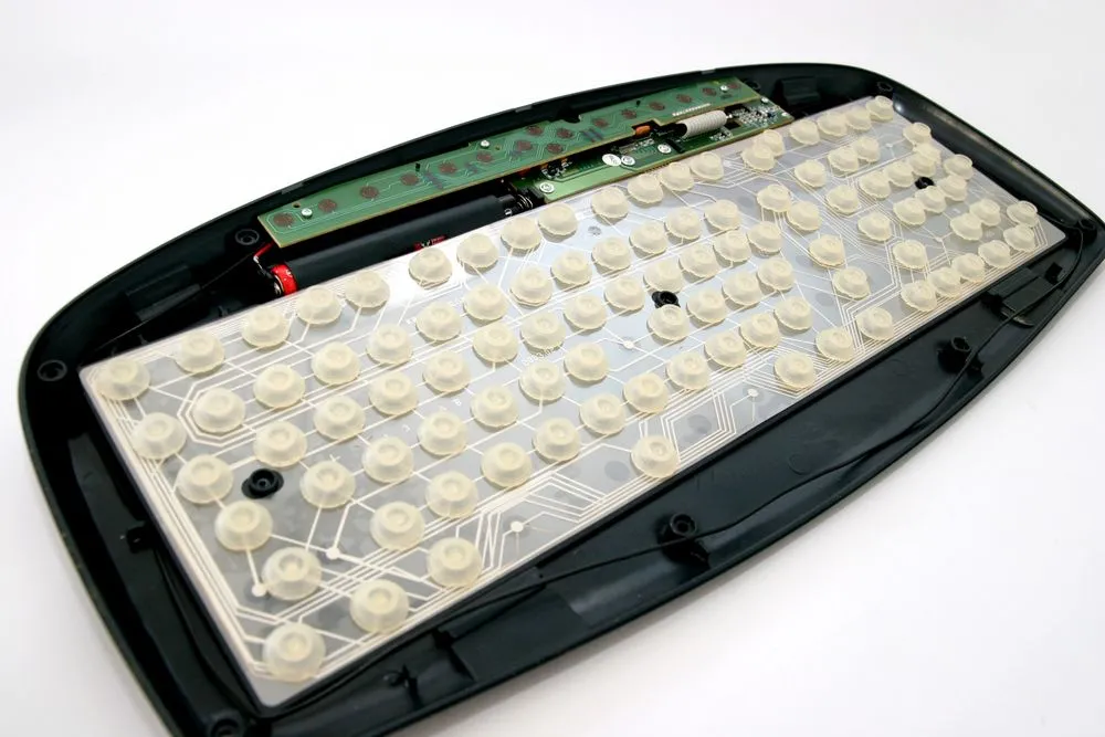 Cận cảnh một bàn phím máy tính đã được tháo rời hoàn toàn, để lộ bảng mạch PCB và các linh kiện bên trong.