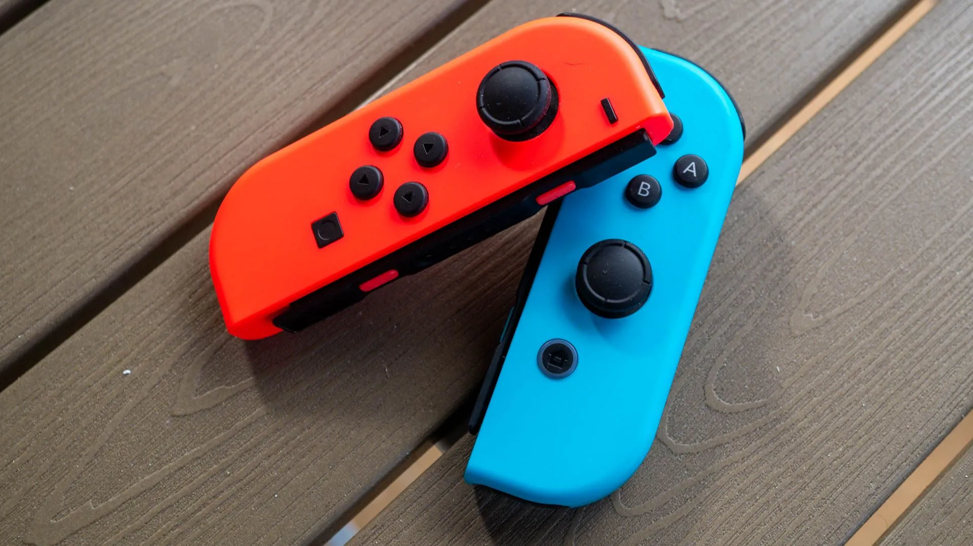 Cặp Joy-Con của Nintendo Switch màu đỏ và xanh lam trên bàn gỗ