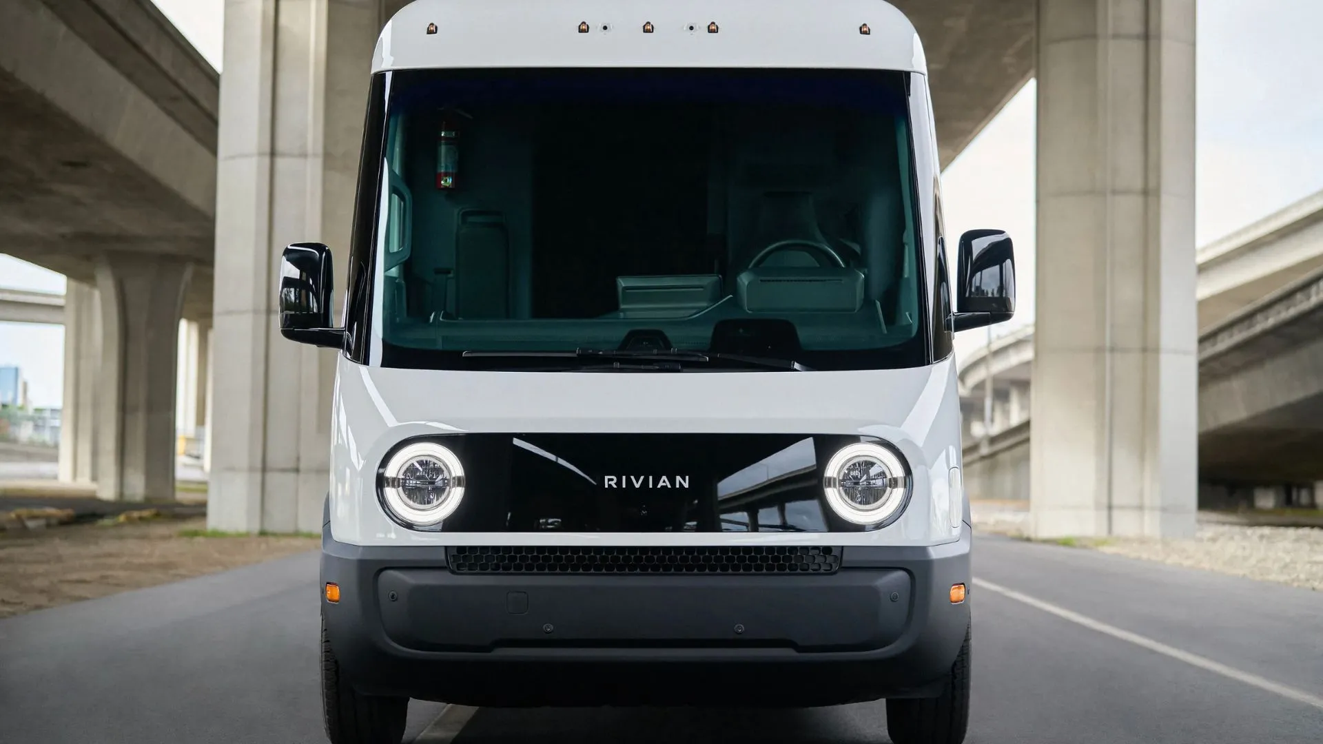 Chiếc xe van điện của Rivian màu xanh navy, được thiết kế cho mục đích giao hàng, đang đậu trên đường phố