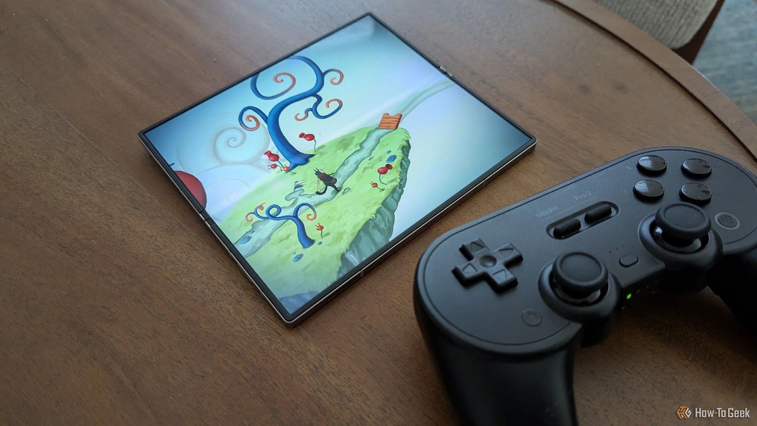 Hình ảnh game Figment trên Galaxy Z Fold 6 bên cạnh tay cầm chơi game 8BitDo Pro 2, minh họa trải nghiệm game di động chất lượng với chi phí hợp lý.