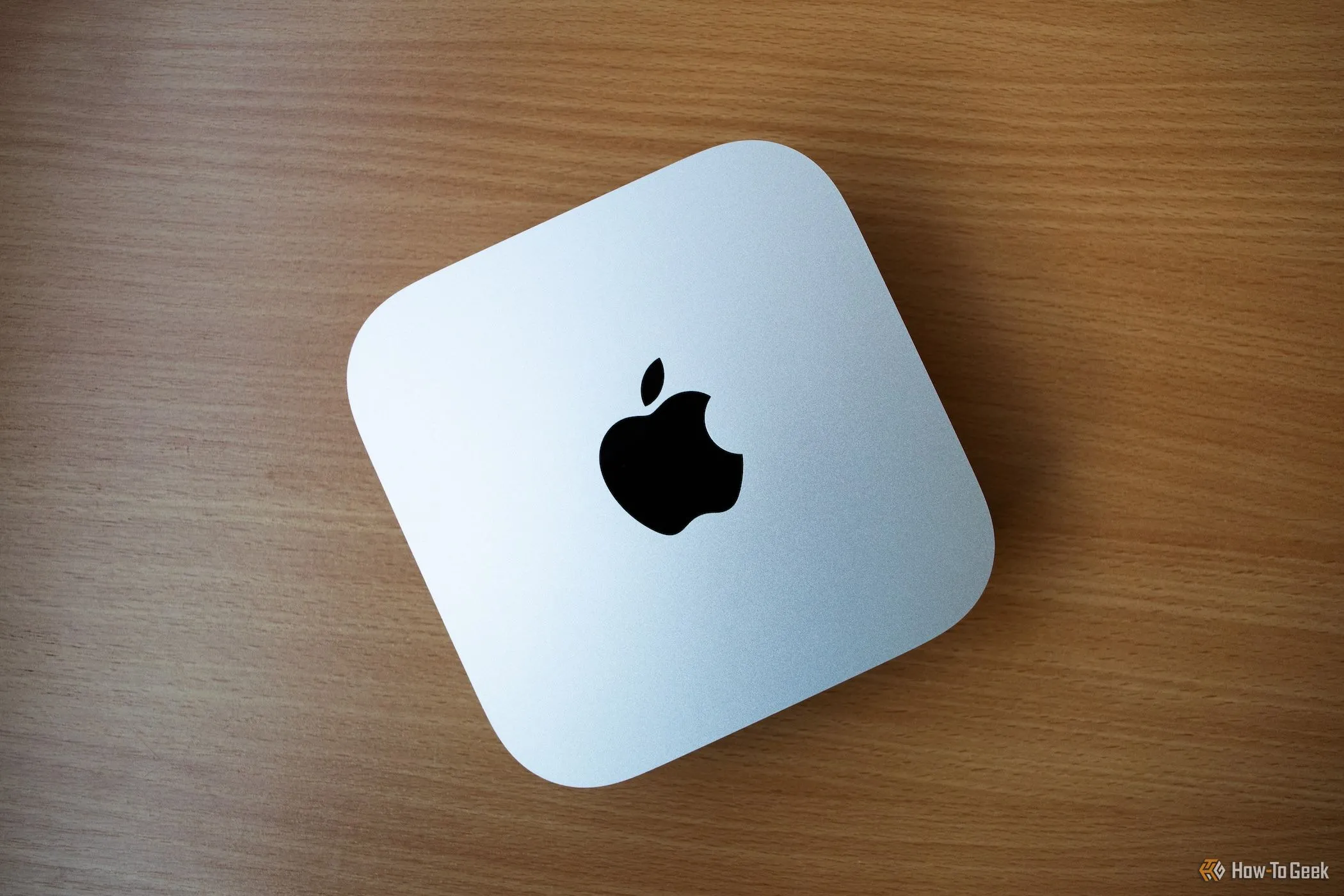 Mac Mini M4 đặt trên bàn gỗ, với thiết kế nhỏ gọn, phù hợp cho gaming dưới TV hoặc không gian hạn chế