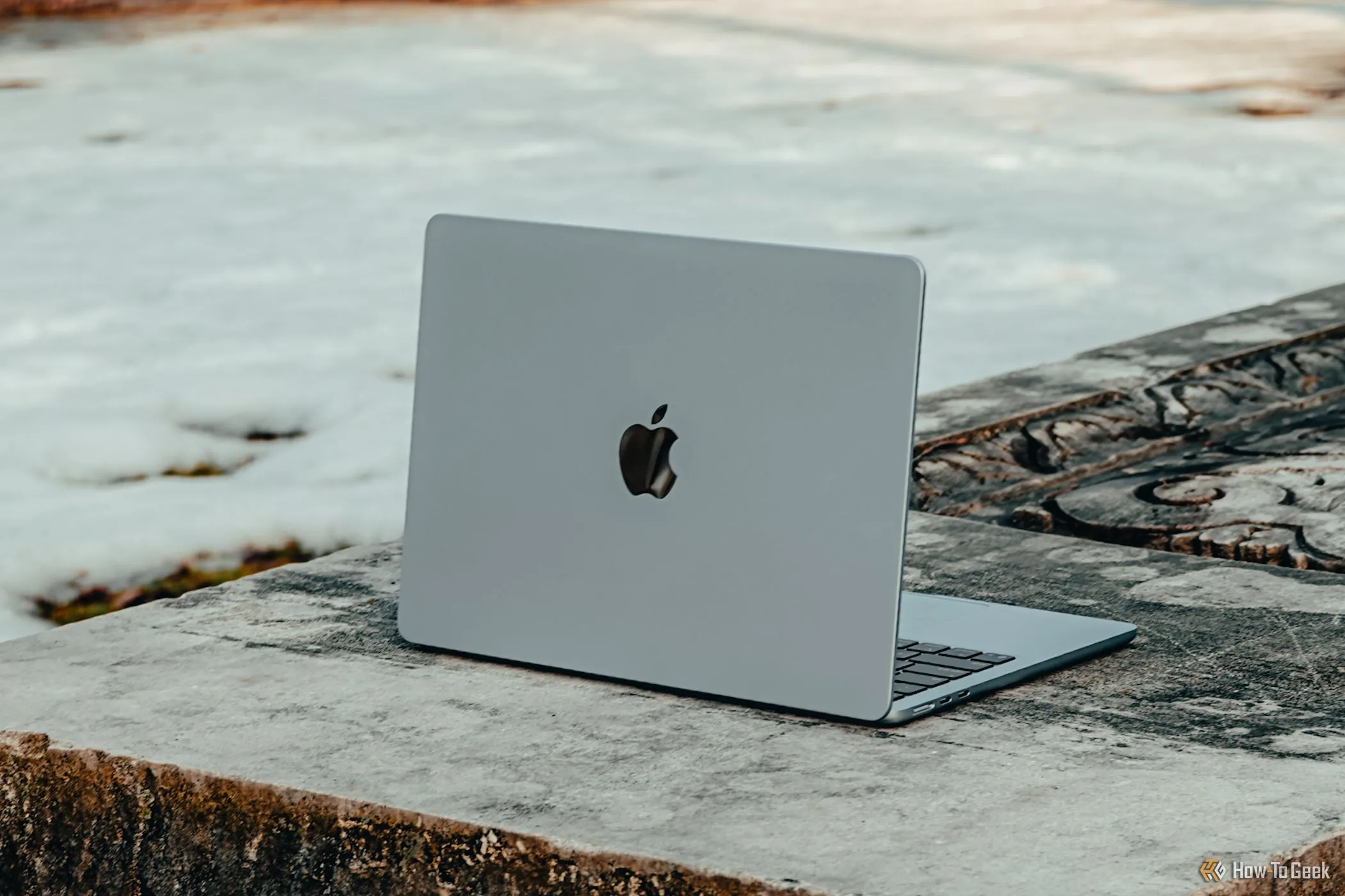 Máy tính xách tay M4 MacBook Air màu xanh lam đặt trên ghế đá bê tông.