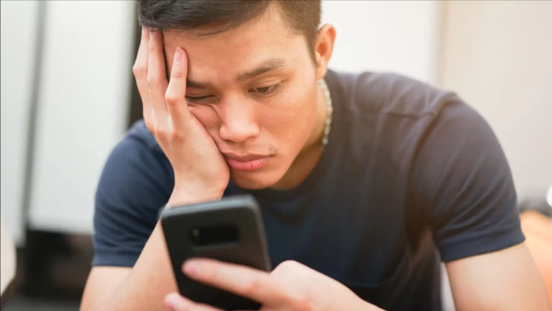 Người dùng điện thoại với vẻ mặt chán nản, thể hiện sự mệt mỏi từ việc lướt mạng xã hội liên tục (doomscrolling) hoặc căng thẳng trong công việc.