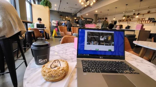 Người dùng làm việc trên laptop tại một quán cà phê, tiềm ẩn nguy cơ khi kết nối Wi-Fi công cộng.