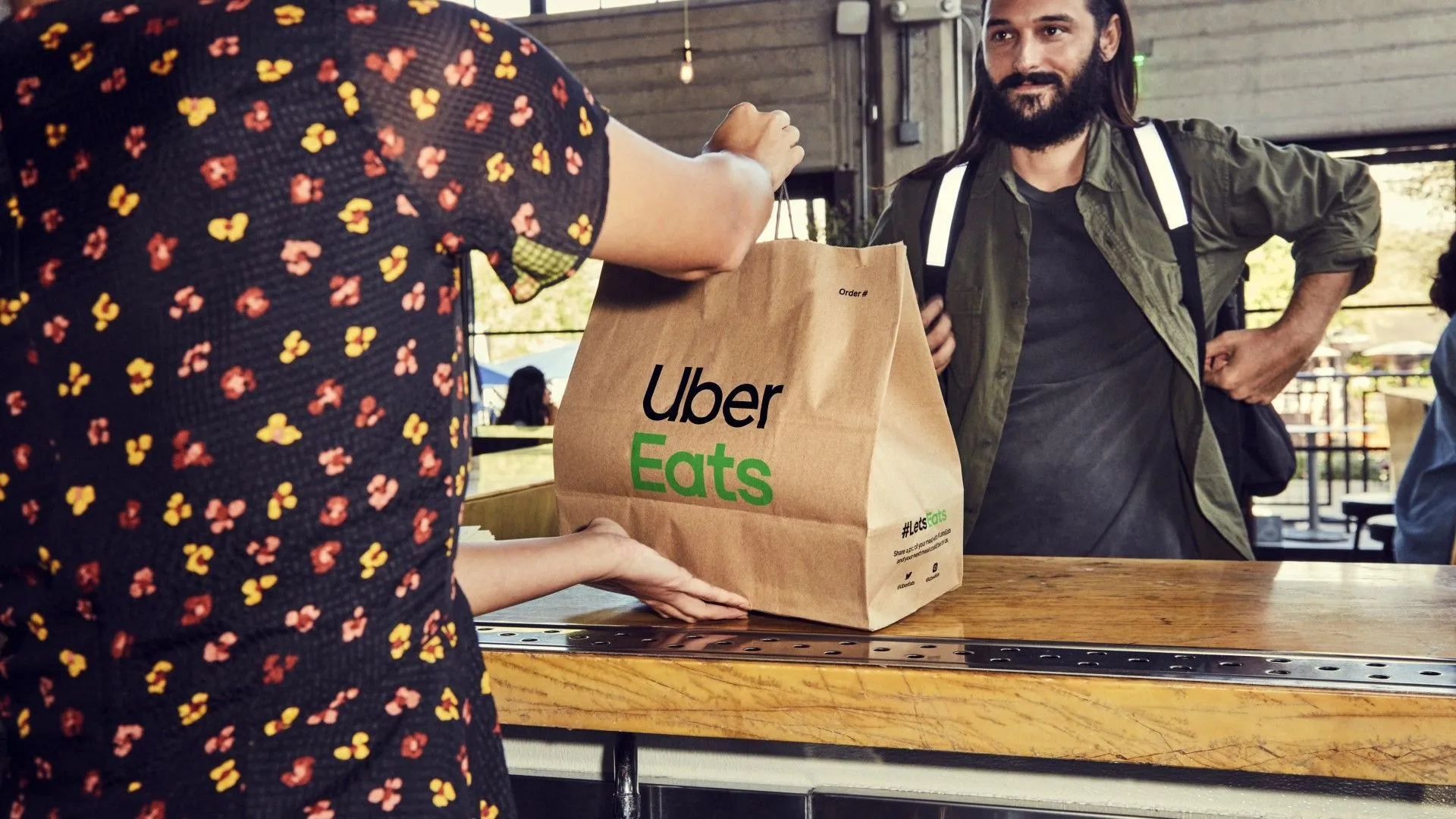 Người giao hàng Uber Eats đang nhận túi đồ ăn từ nhà hàng để bắt đầu chuyến giao hàng kiếm tiền