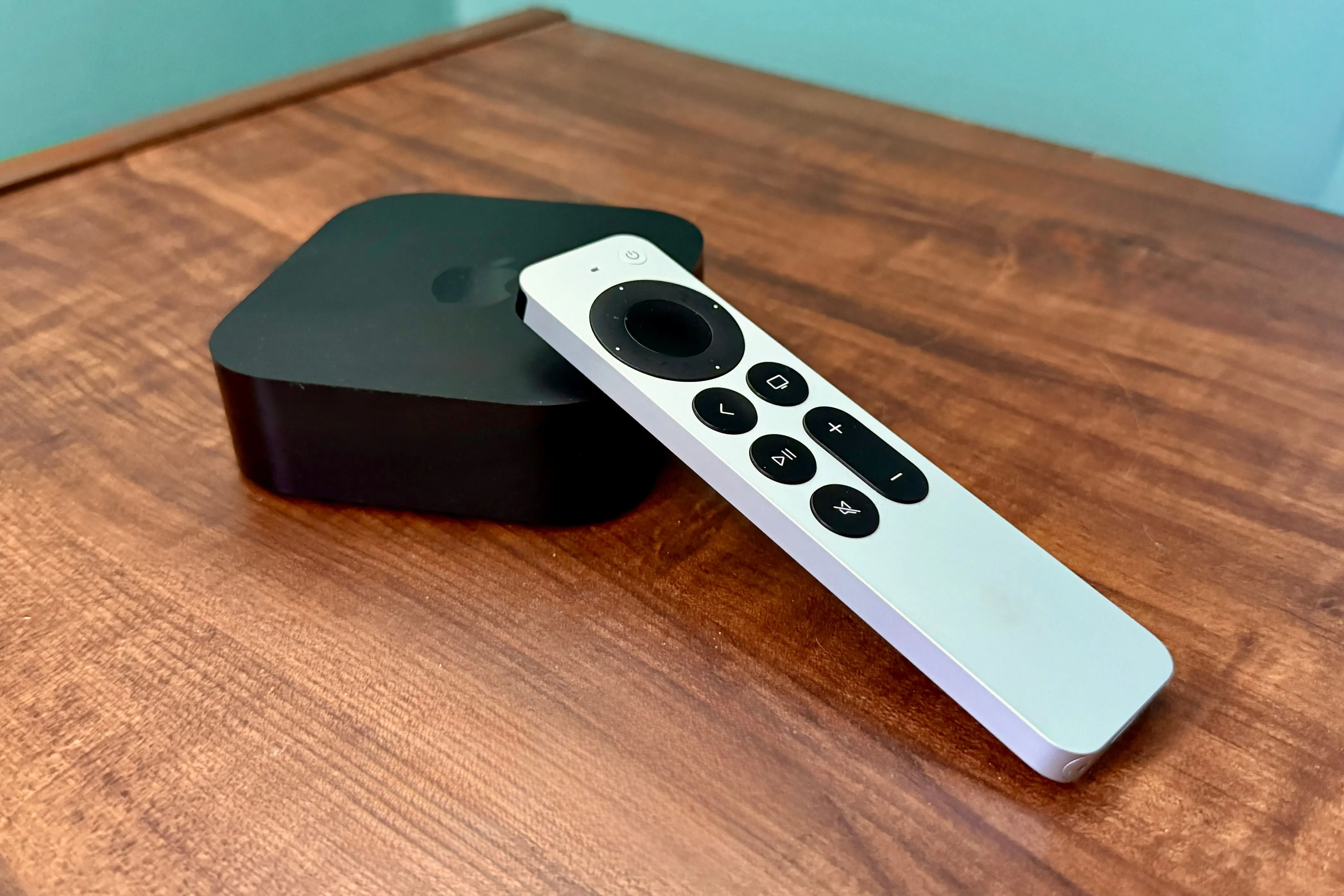 Thiết bị Apple TV 4K và điều khiển Siri Remote đặt trên bàn gỗ, sẵn sàng cho trải nghiệm giải trí và giả lập