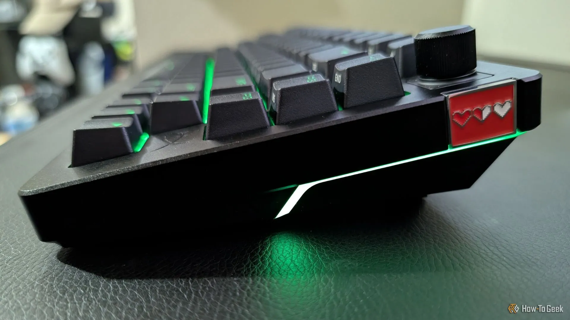 Bàn phím HyperX Alloy Rise 75 với đèn nền RGB màu xanh lá và huy hiệu từ tính tùy chỉnh, thể hiện khả năng cá nhân hóa