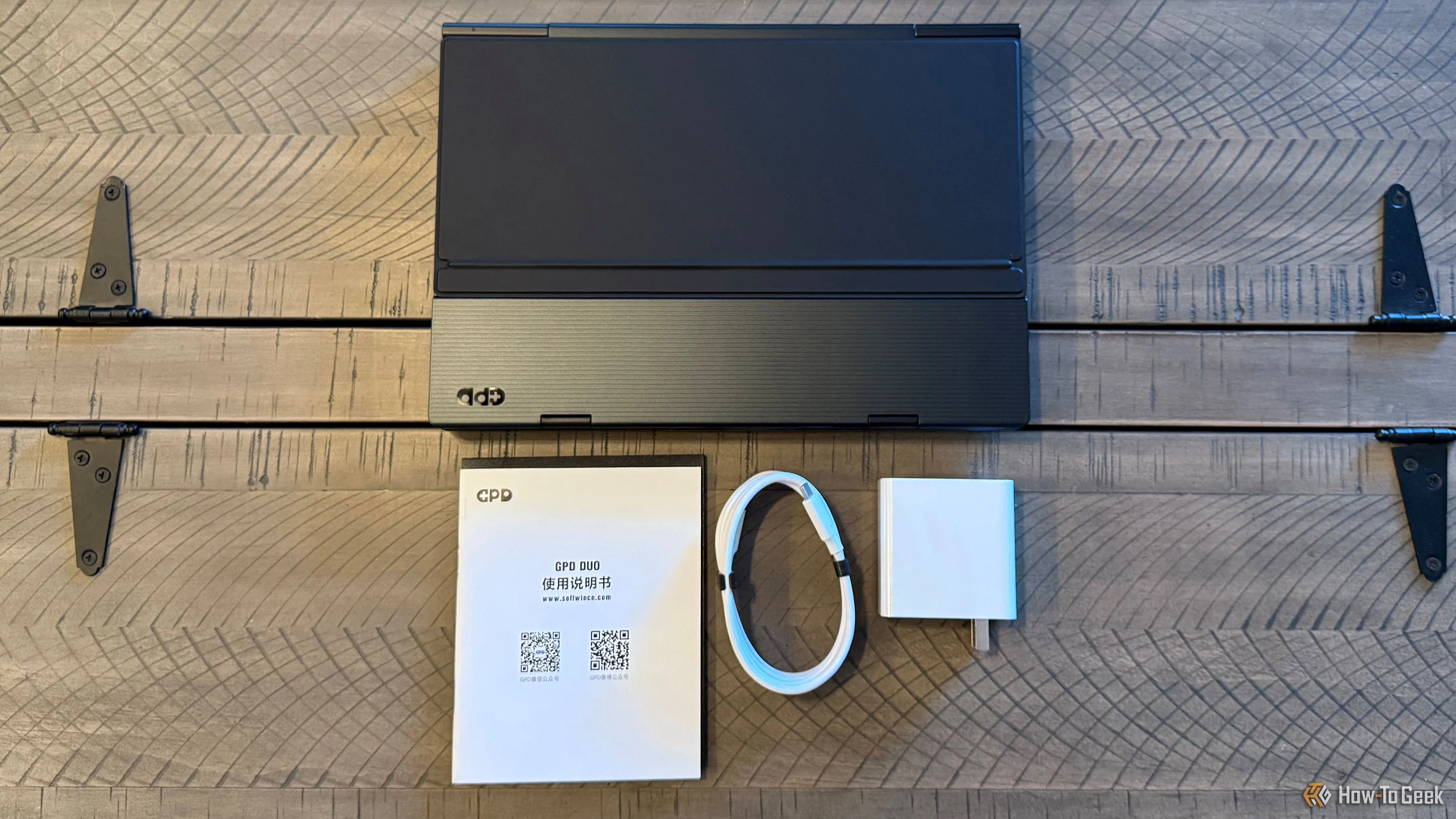 Bên trong hộp GPD Duo: laptop, sạc USB-C và cáp kết nối trên mặt bàn