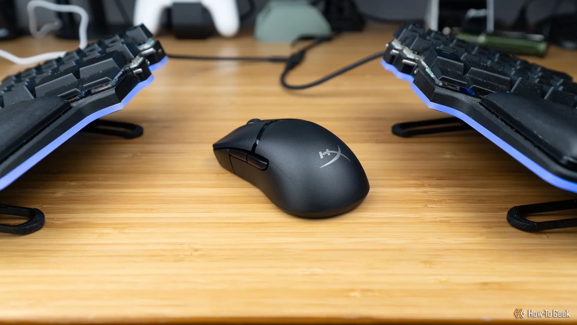 Chuột gaming HyperX Pulsefire Saga Pro đặt giữa hai nửa bàn phím cơ tùy chỉnh.