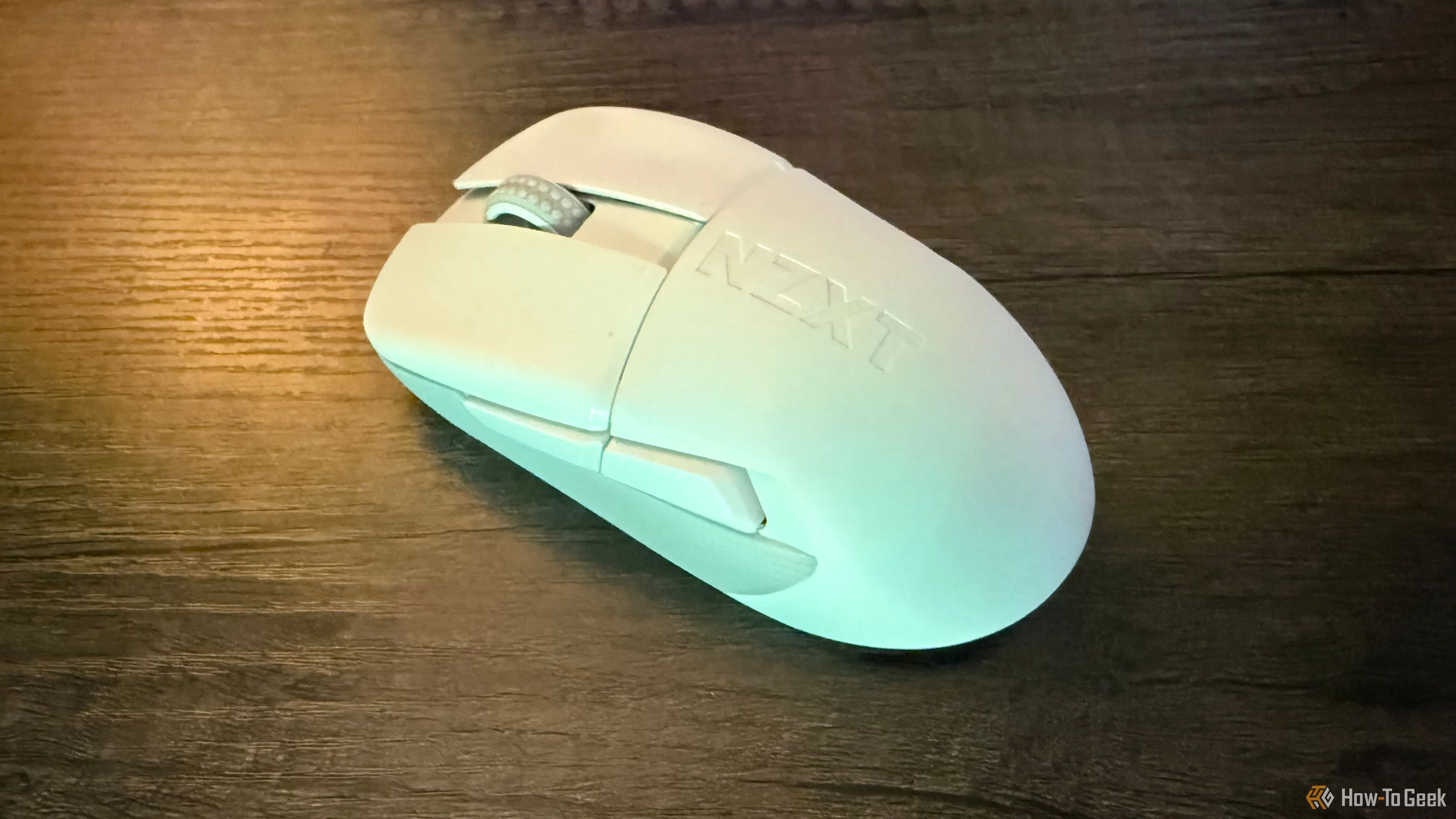 Chuột NZXT Lift Elite Wireless được đặt trên bàn làm việc cùng với tấm lót chuột, thể hiện kích thước và thiết kế công thái học.