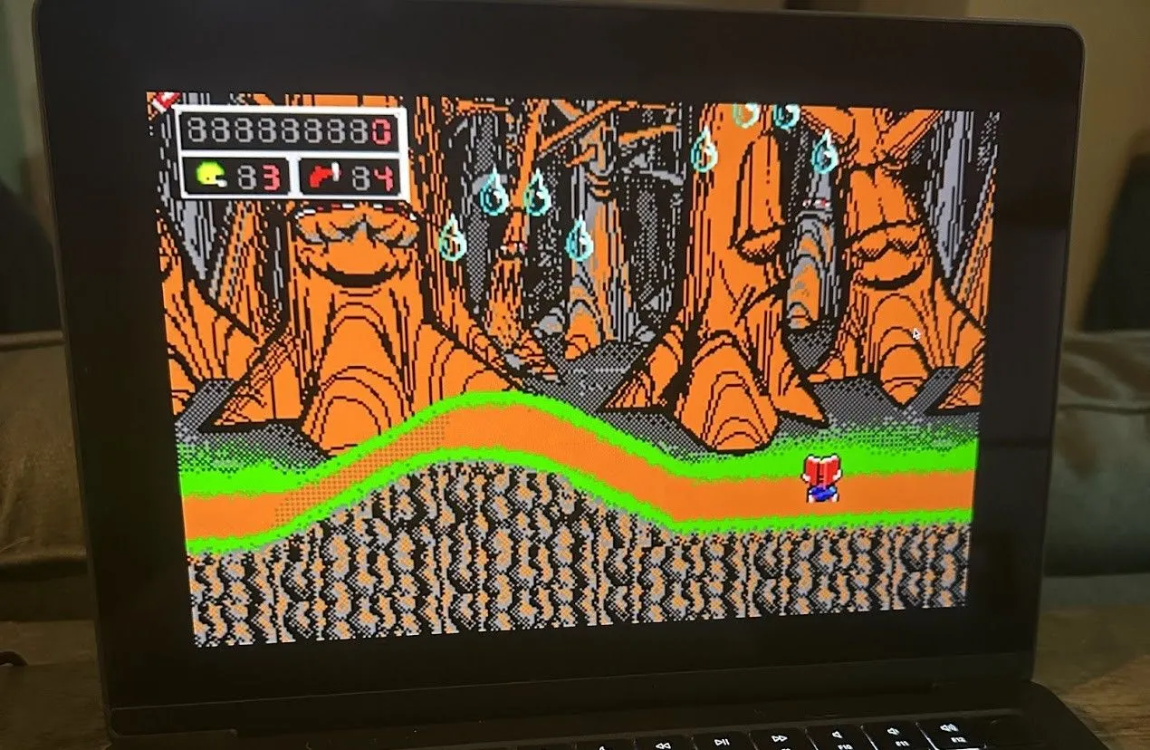 Commander Keen, nhân vật chính với chiếc mũ bóng chày xanh, đang nhảy qua các chướng ngại vật trong môi trường game 2D cổ điển trên màn hình MacBook Pro.