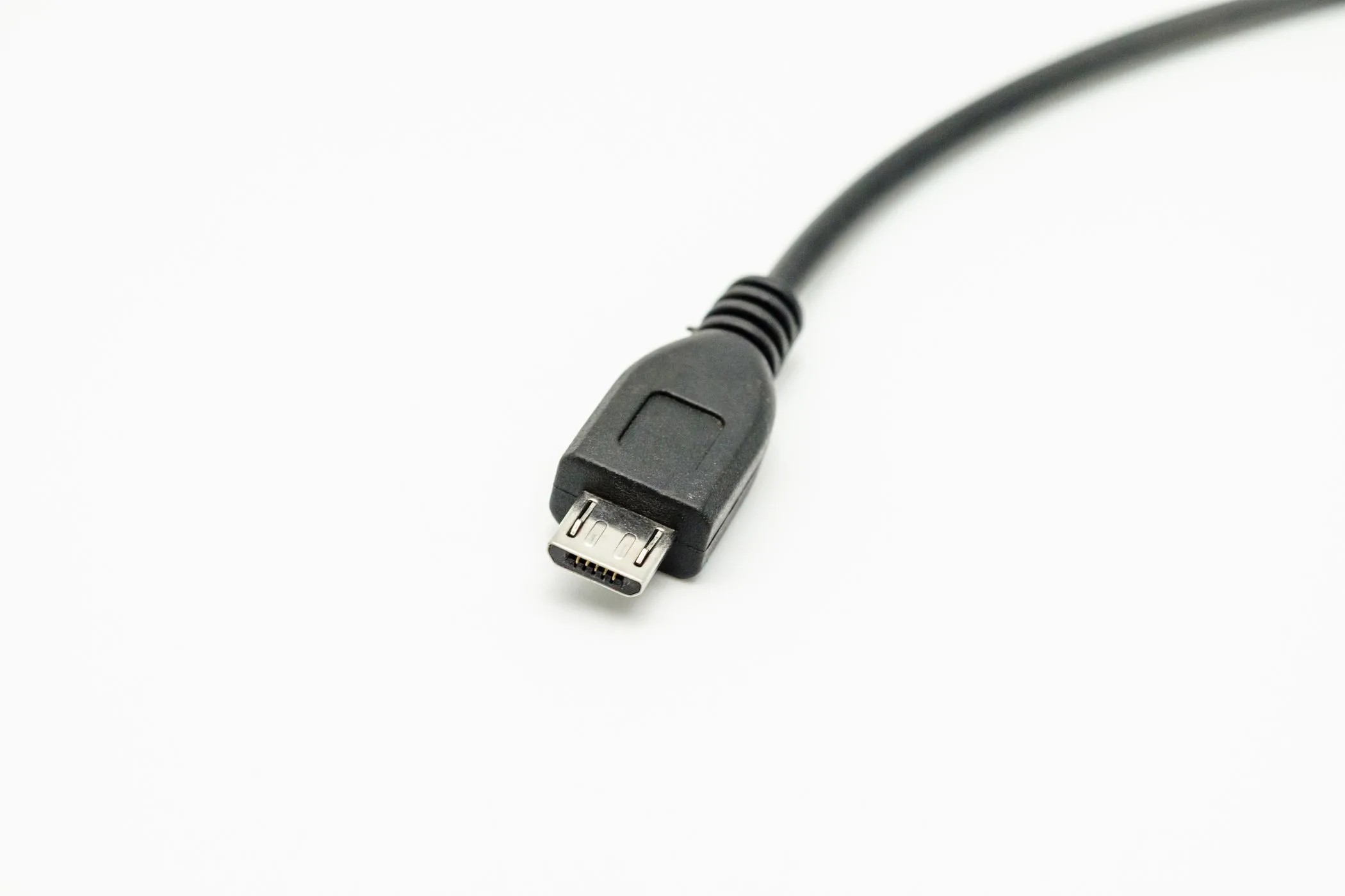 Dây cáp Micro-USB màu đen nằm trên nền trắng, gợi nhớ về một chuẩn kết nối phổ biến trên các thiết bị cũ.