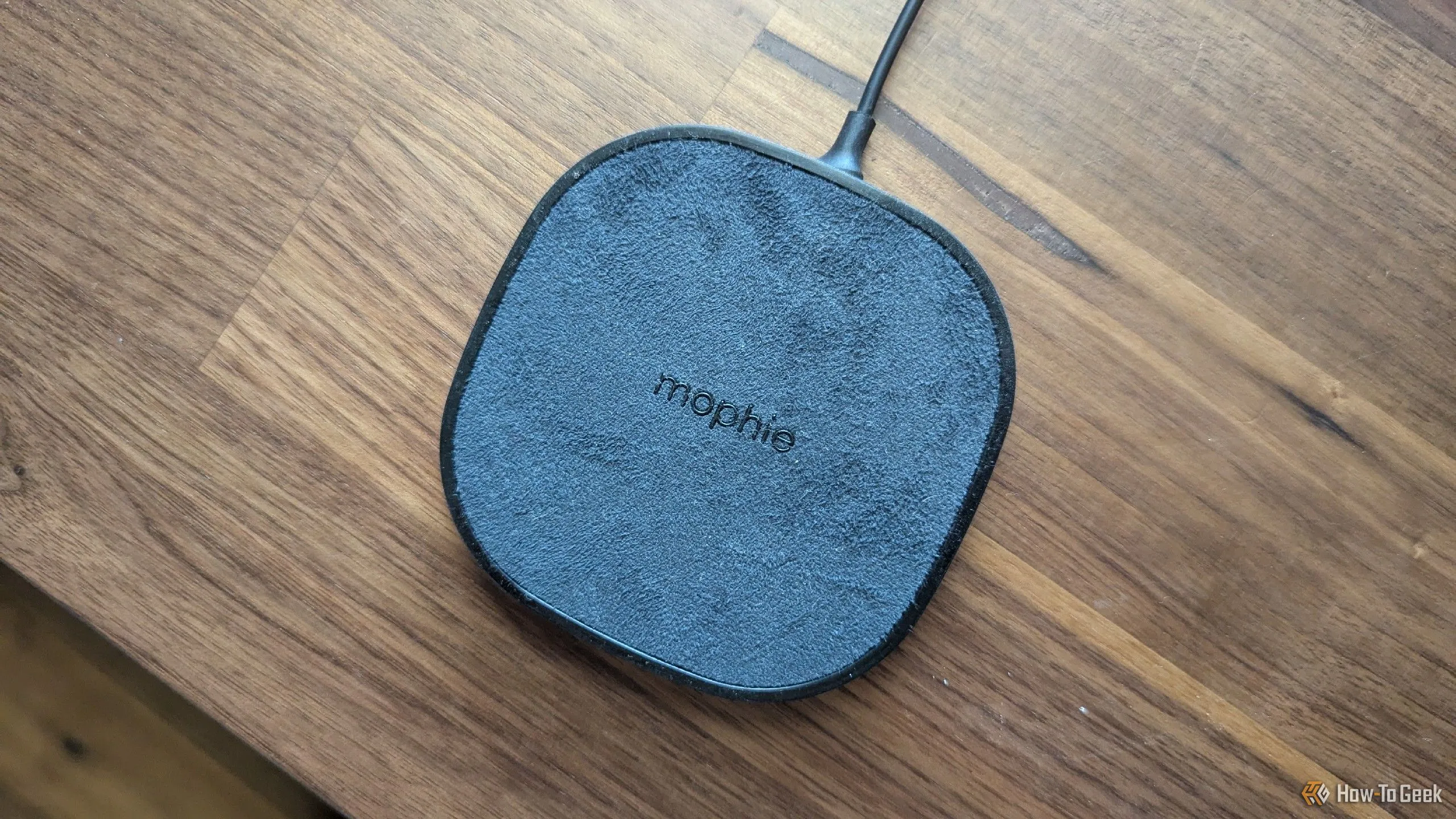Đế sạc không dây Mophie nhỏ gọn được đặt trên bàn, sẵn sàng sạc cho thiết bị khi bạn làm việc nhà