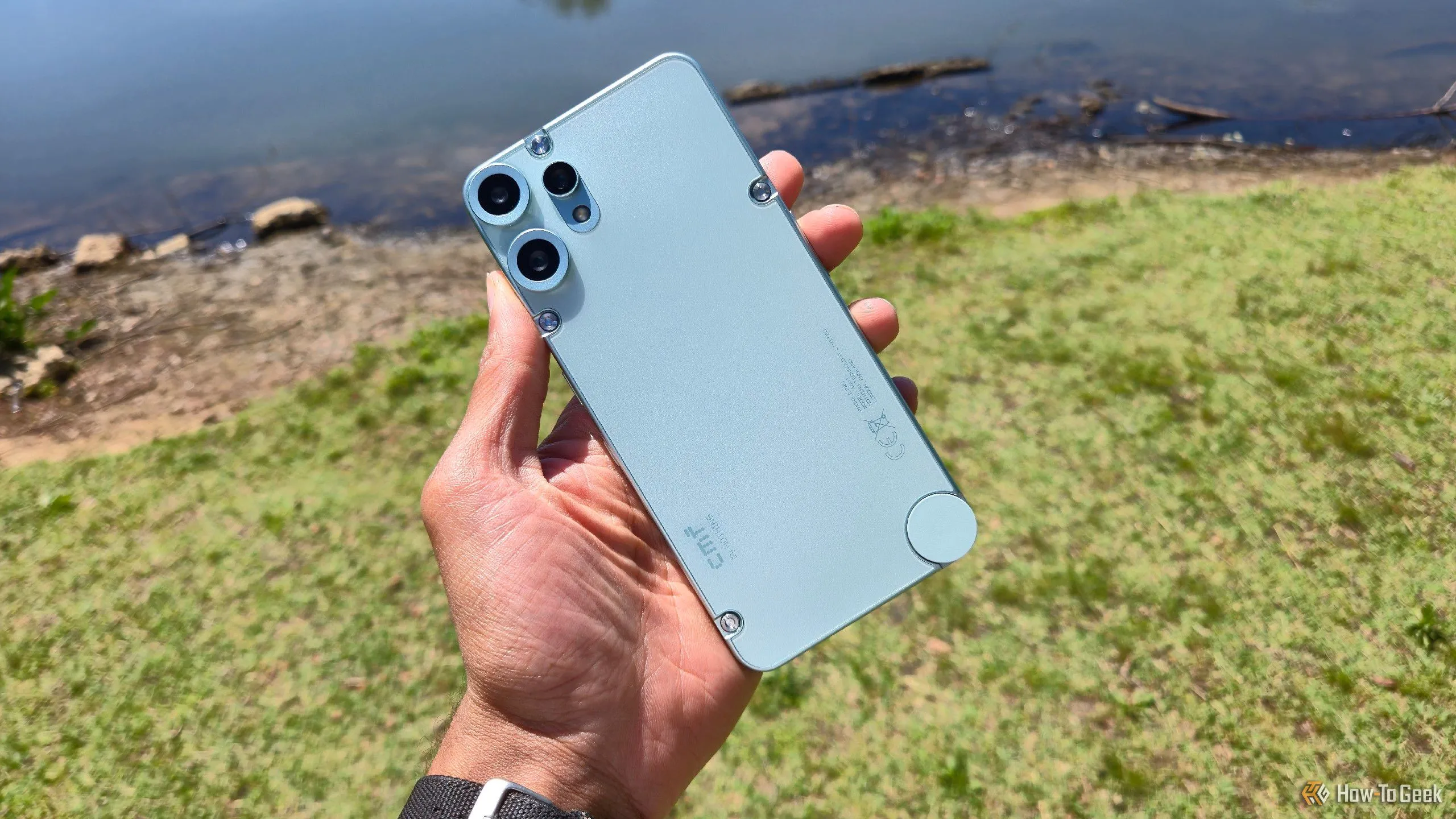 Điện thoại CMF Phone 2 Pro màu đen đặt trước khung cảnh hồ nước, làm nổi bật thiết kế mặt lưng và cụm camera, được so sánh với Nothing Phone 3.
