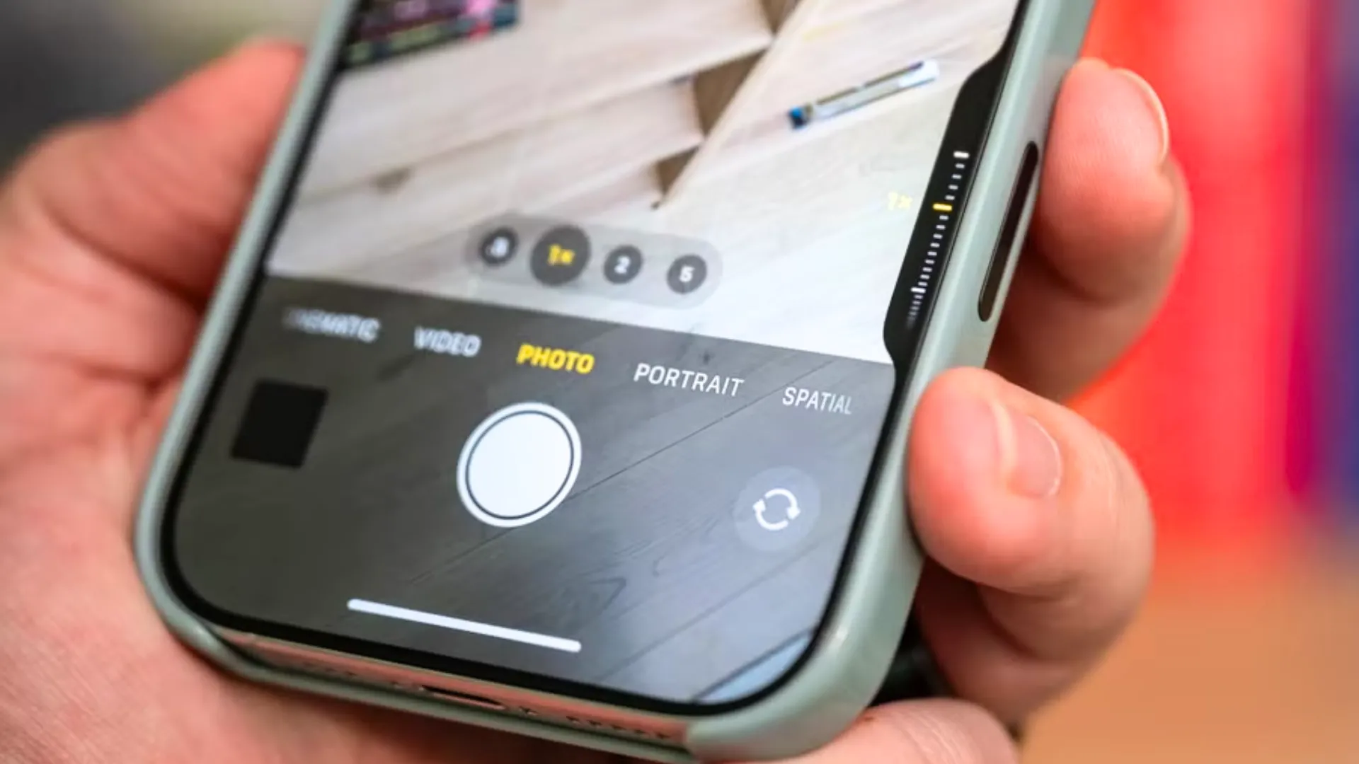 iPhone 16 Plus được cầm trên tay, hiển thị nút Điều khiển Camera vật lý ở góc trên bên phải.