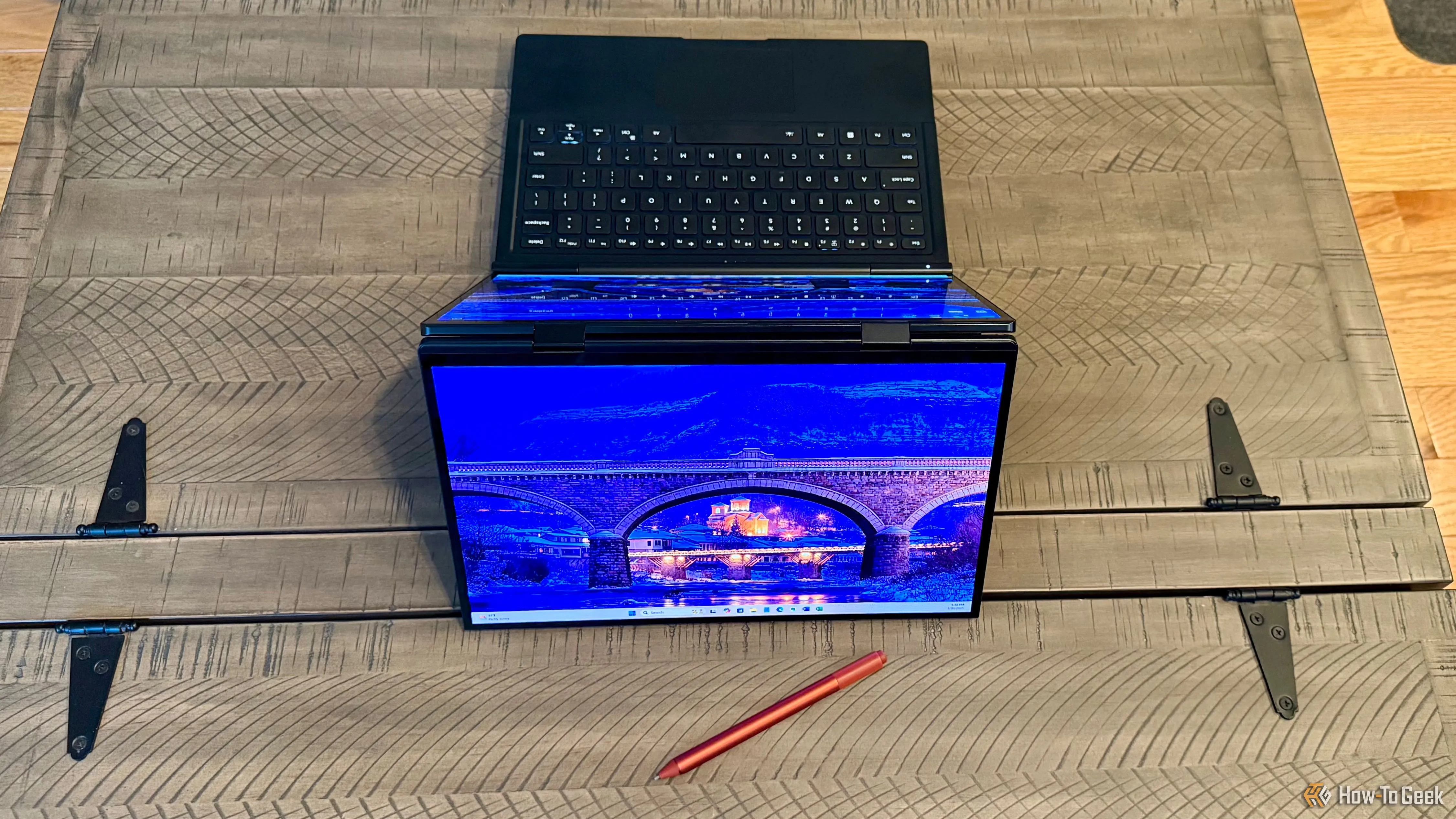 Laptop GPD Duo gập ngược, hiển thị màn hình phụ hướng ra ngoài, bên cạnh là bút cảm ứng