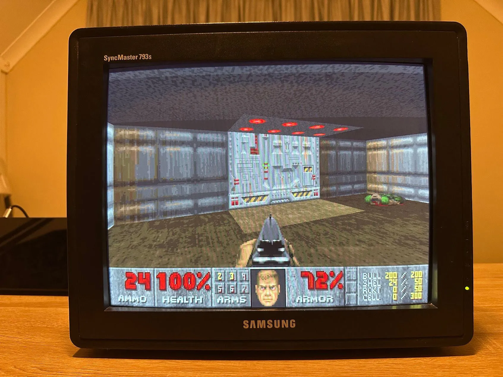 Màn hình máy tính cũ hiển thị game DOOM góc nhìn thứ nhất với đồ họa pixel cổ điển.
