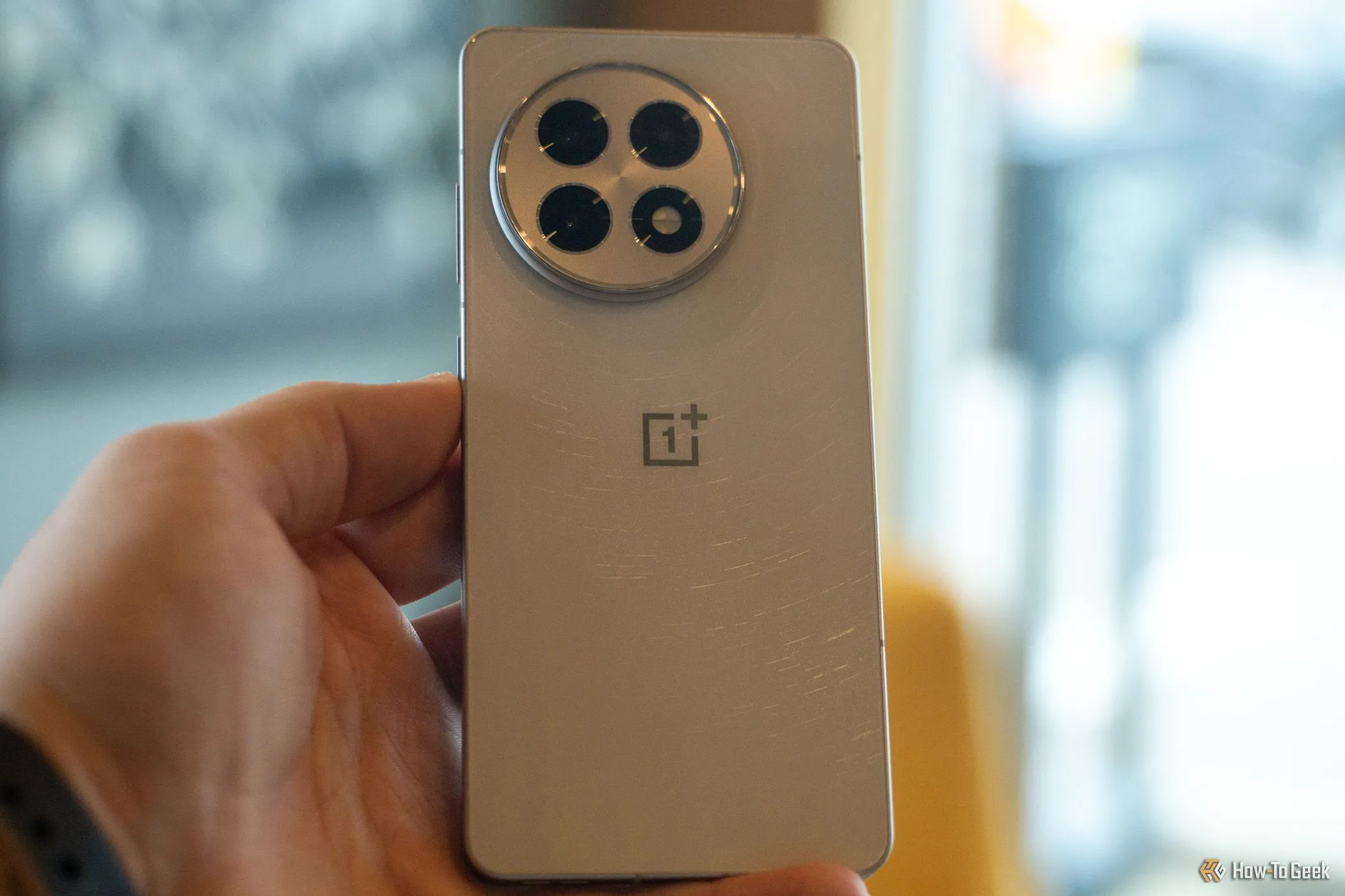 Mặt lưng của điện thoại OnePlus 13R trong lòng bàn tay, cho thấy thiết kế và chất liệu cao cấp