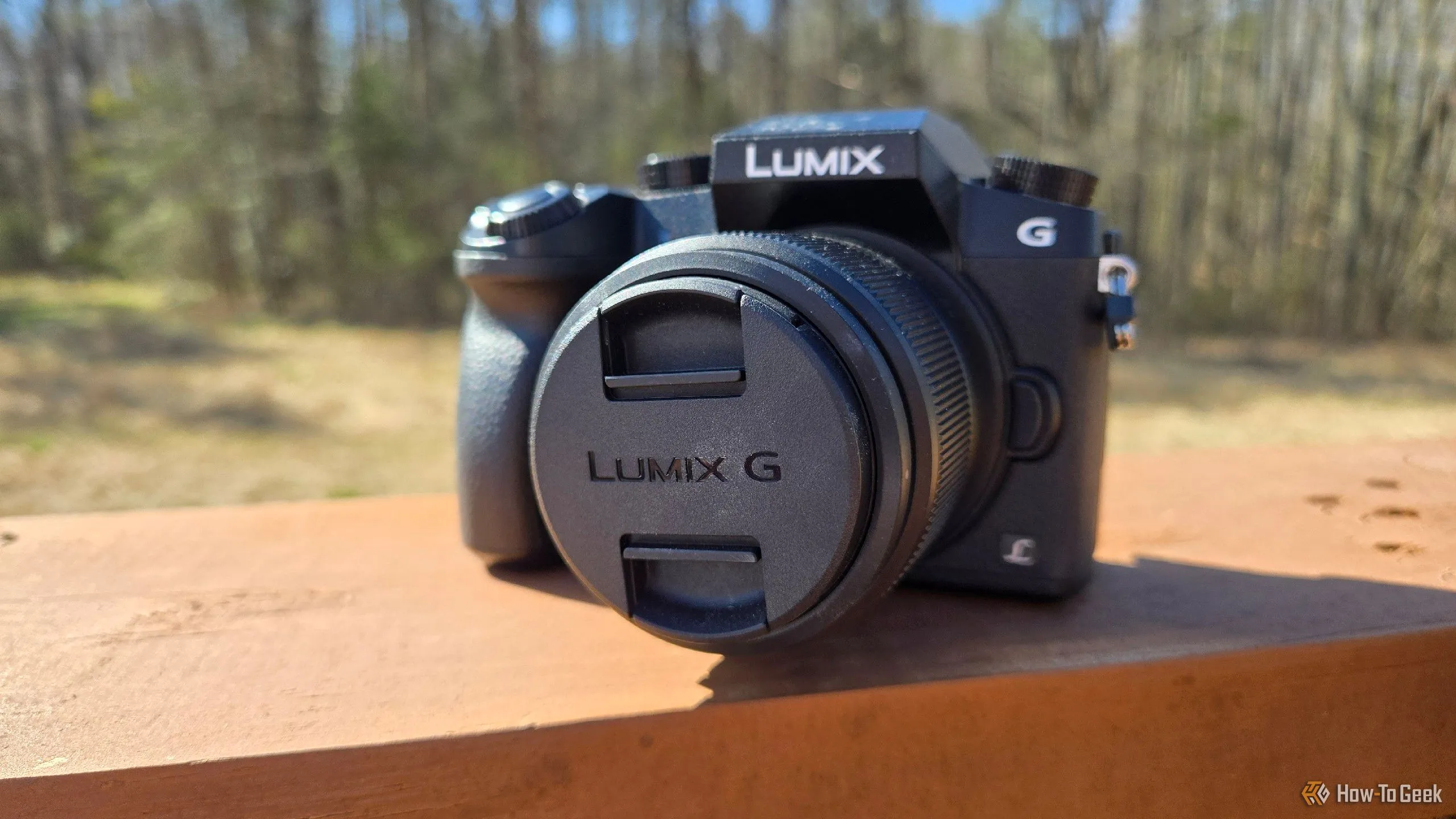 Máy ảnh mirrorless Panasonic Lumix G7 đặt trên lan can, minh họa sự khác biệt và ưu thế của cảm biến lớn so với camera điện thoại.