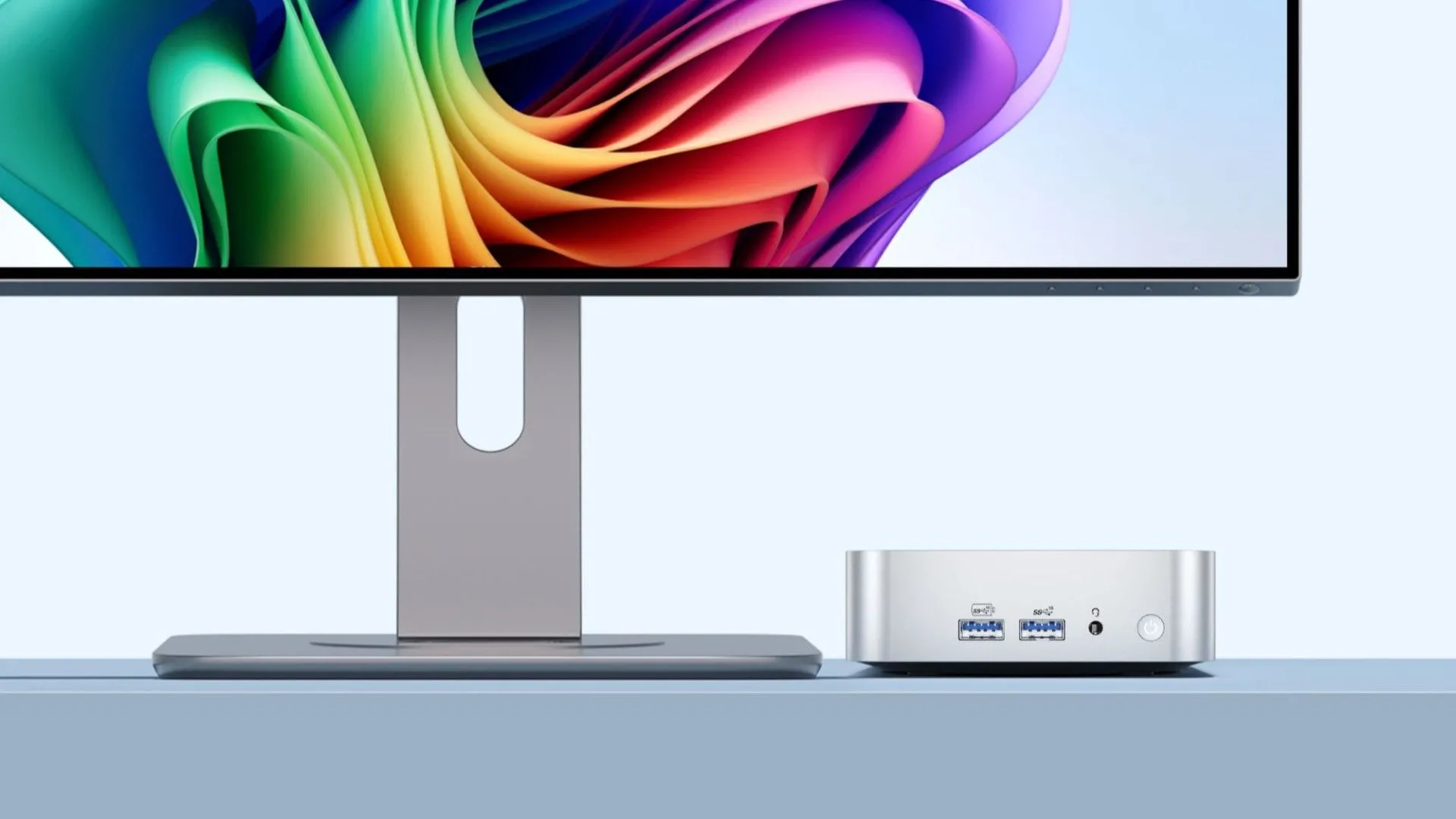 Mini PC GEEKOM A6 màu xám bạc đặt trên bàn làm việc, kết nối với màn hình, cho thấy sự nhỏ gọn và mạnh mẽ trong một thiết kế hiện đại.