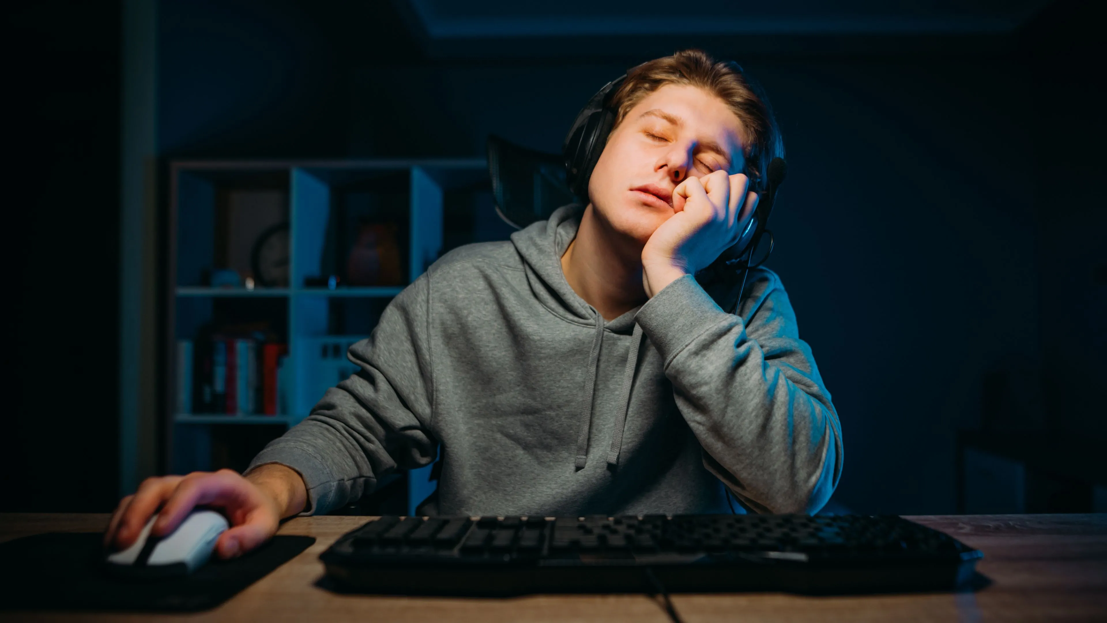 Một game thủ buồn ngủ gục trên bàn làm việc, thể hiện mong muốn có chế độ ngủ tức thì như máy tính