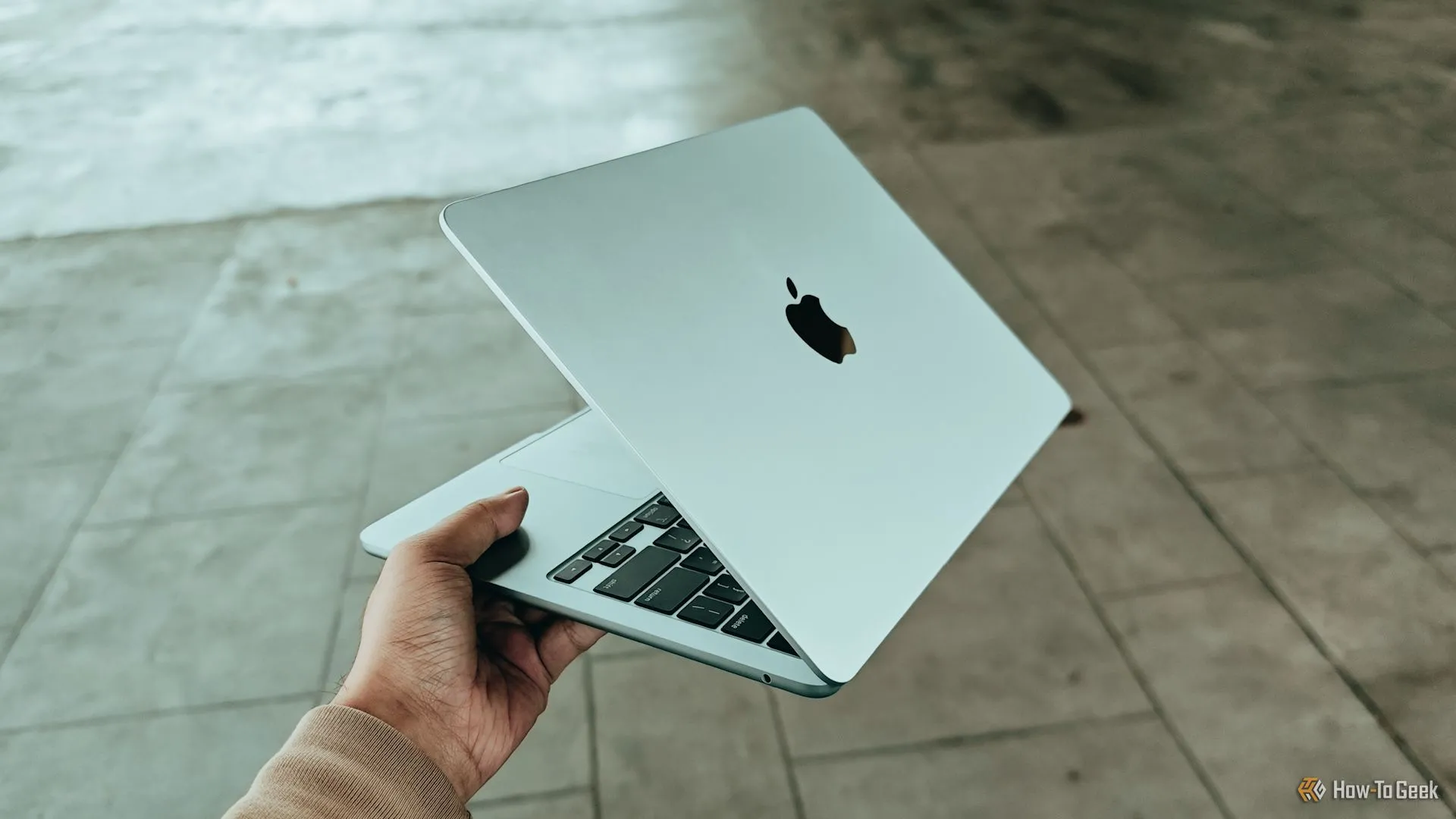 Người dùng cầm MacBook Air M4, hình dung về tương lai MacBook tích hợp 5G tiện lợi cho di chuyển.