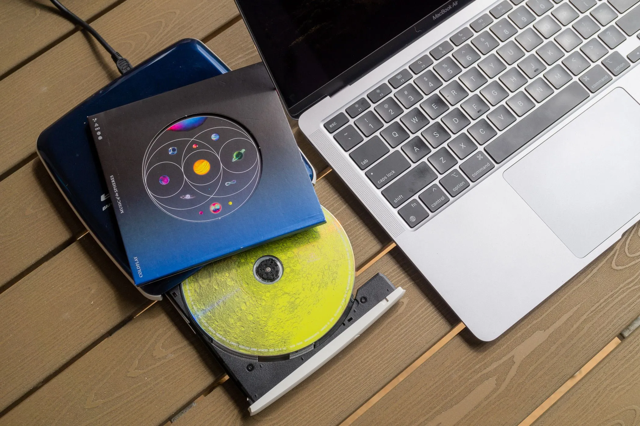Ổ đĩa CD và đĩa nhạc CD bên cạnh MacBook Air.