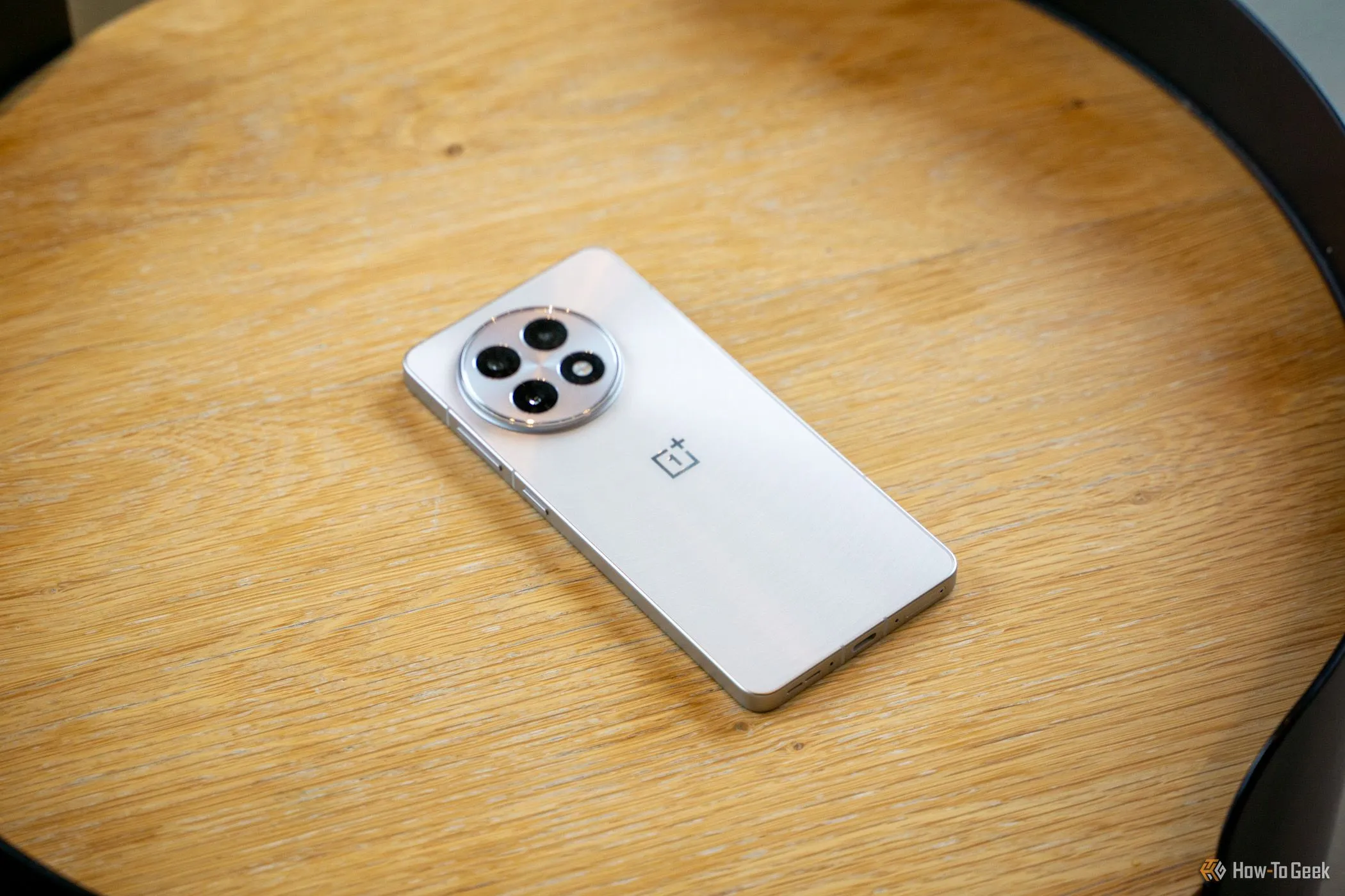 OnePlus 13R đặt úp trên bàn gỗ, để lộ cụm camera sau nổi bật