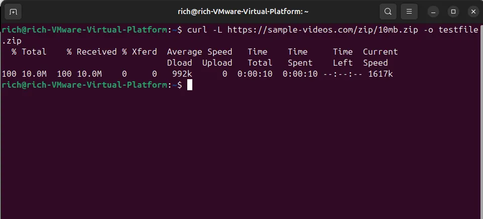 Output Terminal hiển thị lệnh curl -L tải file ZIP 10MB và lưu dưới tên testfile.zip trên Linux.