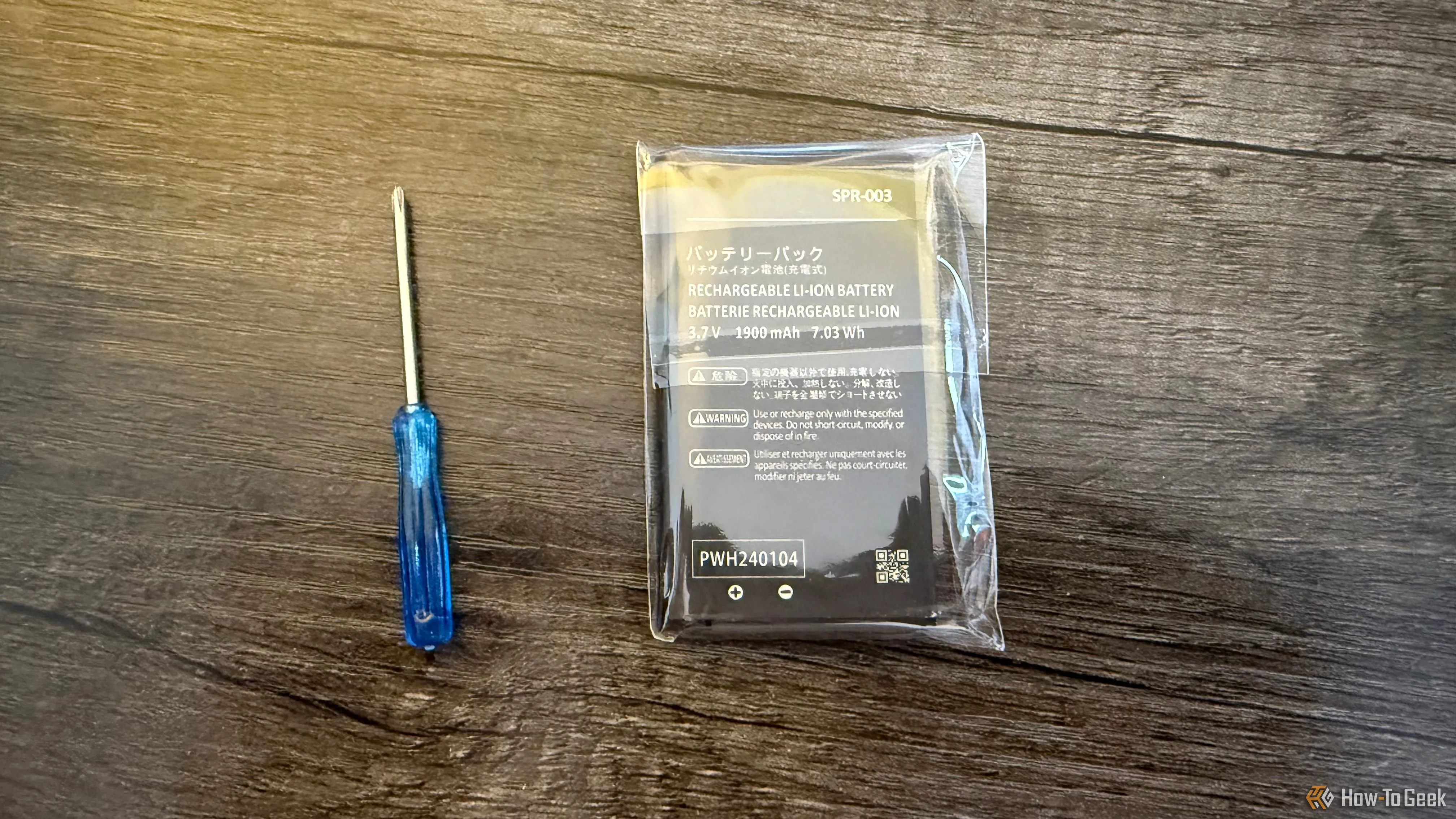 Pin thay thế cho Nintendo 3DS được bảo quản trong hộp nhựa, đặt cạnh tuốc nơ vít, minh họa các vật phẩm cần thiết để thay pin.