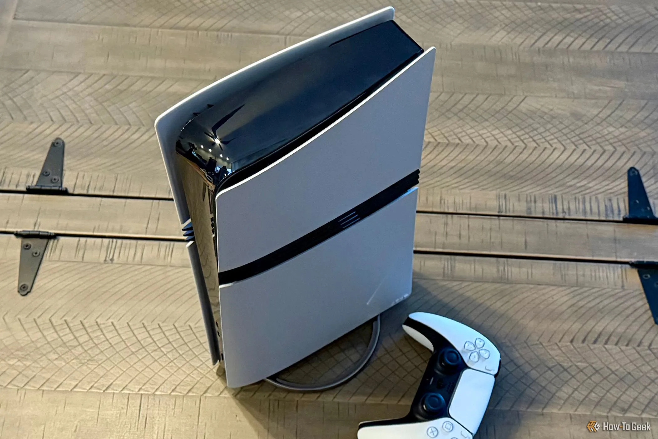 Sony PlayStation 5 Pro màu trắng với chân đế dọc đặt bên cạnh tay cầm không dây DualSense