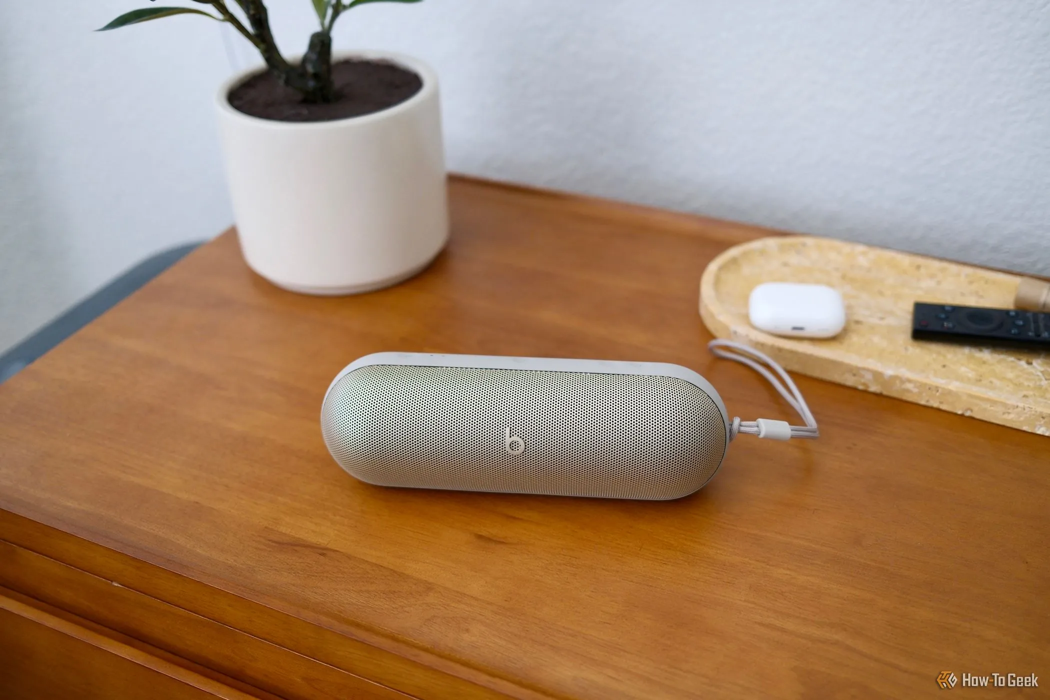 Tai nghe Beats Pill màu đen nằm trên bàn gỗ cạnh bình nước và sách