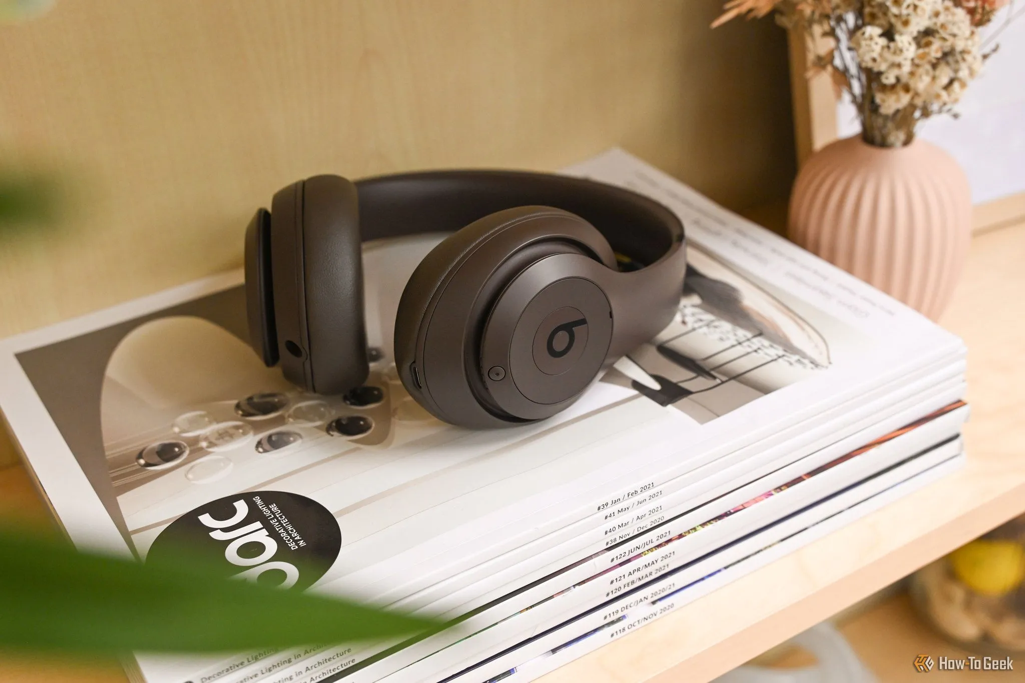 Tai nghe Beats Studio Pro màu nâu đậm đặt trên một chồng tạp chí, biểu tượng của phong cách và âm thanh