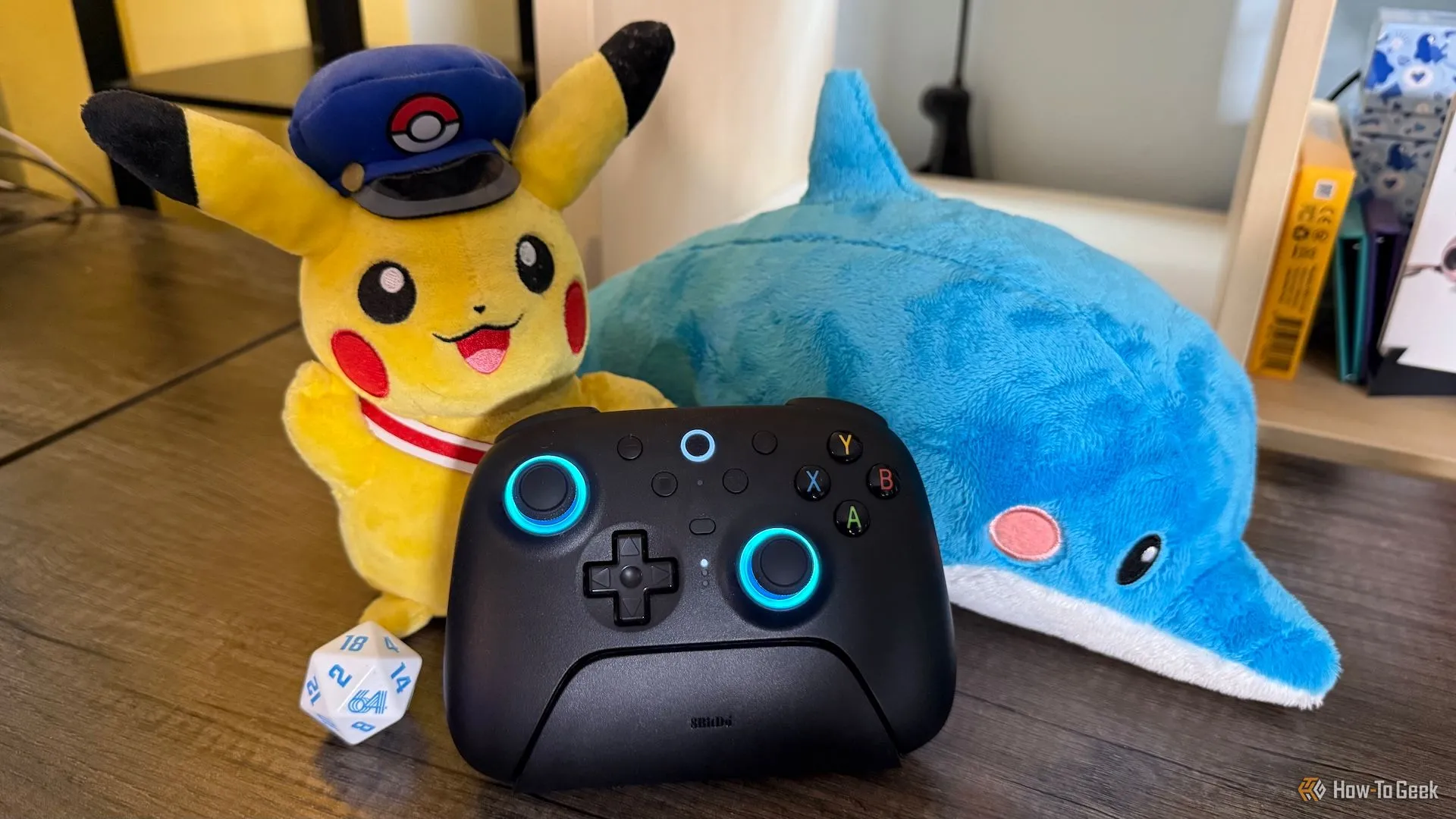 Tay cầm 8BitDo Ultimate 2 Wireless trên dock sạc cùng các vật trang trí gaming