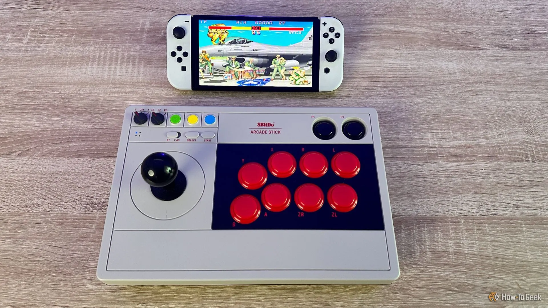 Tay cầm chơi game 8BitDo Arcade Stick đang được sử dụng để chơi Street Fighter 2 trên máy Nintendo Switch OLED, minh họa trải nghiệm game thủ.