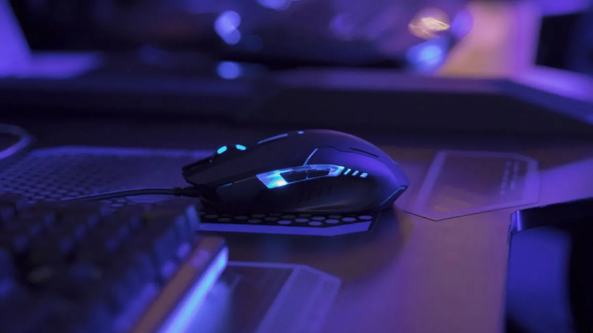 Chuột gaming với đèn nền LED xanh trên bàn máy tính, minh họa trải nghiệm chơi game chuyên nghiệp