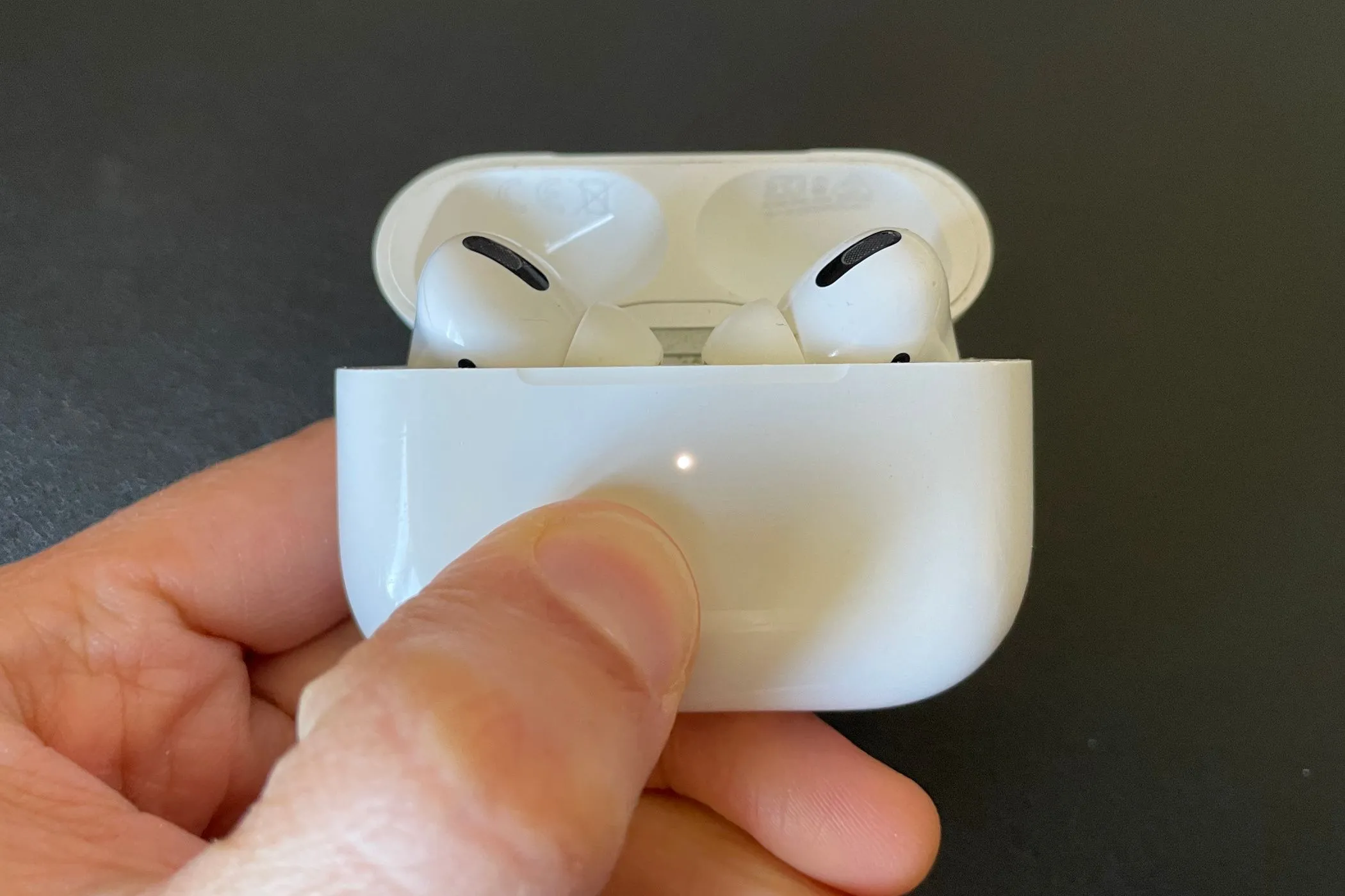 Hộp sạc AirPods Pro đang mở, hiển thị hai tai nghe bên trong và đèn trạng thái màu trắng, tượng trưng cho quá trình sạc hoặc kết nối.