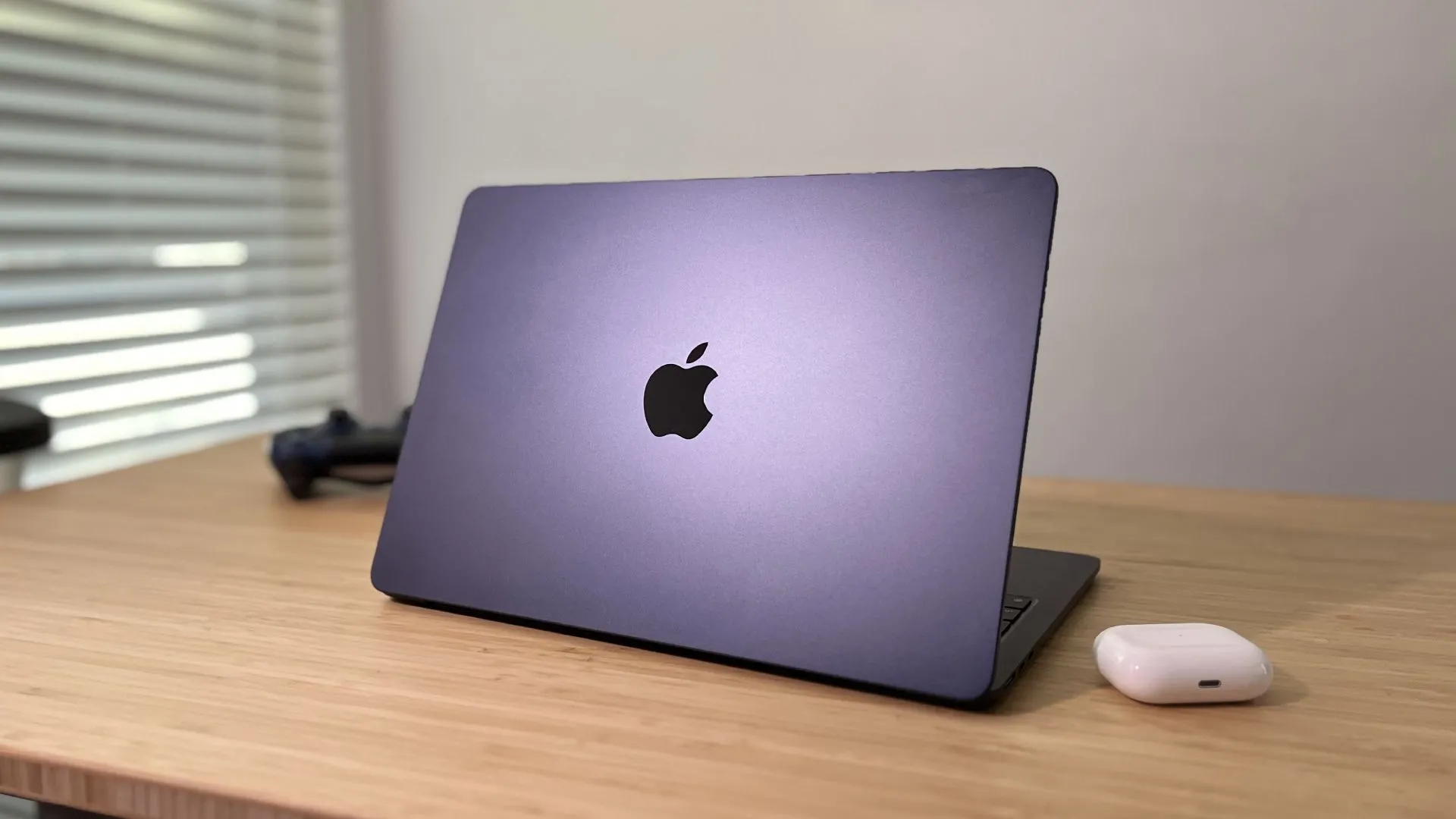 MacBook Air M2 màu Midnight với màn hình hiển thị hệ điều hành macOS, đặt nghiêng trên bề mặt