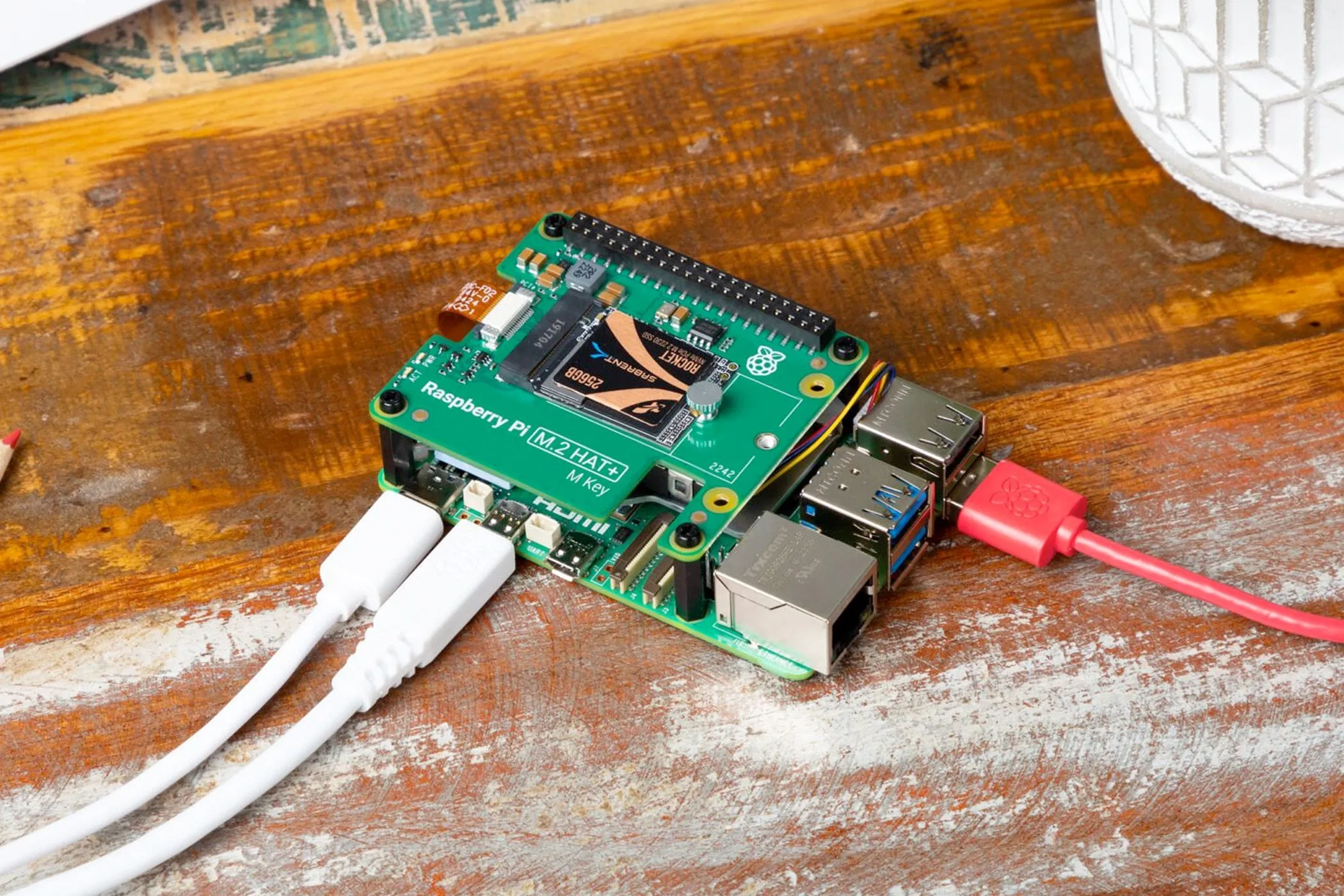 Máy tính Raspberry Pi với các dây cáp kết nối trên bề mặt gỗ, so sánh với sự gọn nhẹ của Mini PC.