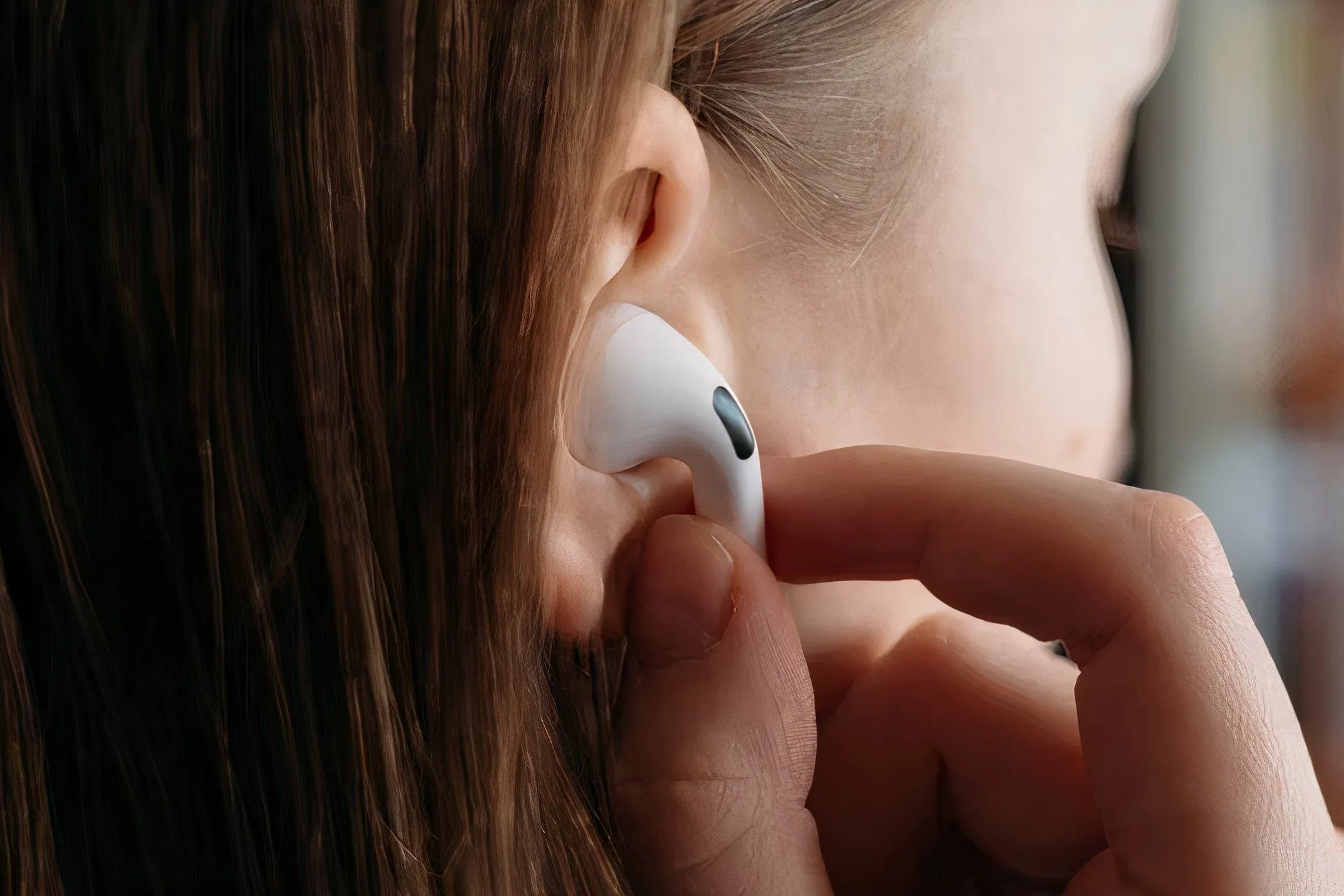 Một người phụ nữ đang đeo tai nghe AirPods Pro vào tai, thể hiện sự tiện lợi của tai nghe không dây trong cuộc sống hàng ngày.