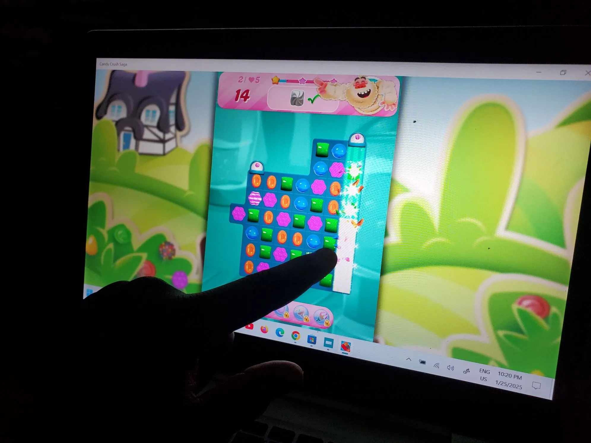 Người dùng chơi game Candy Crush trên laptop có màn hình cảm ứng, thể hiện sự tương thích với các tựa game casual