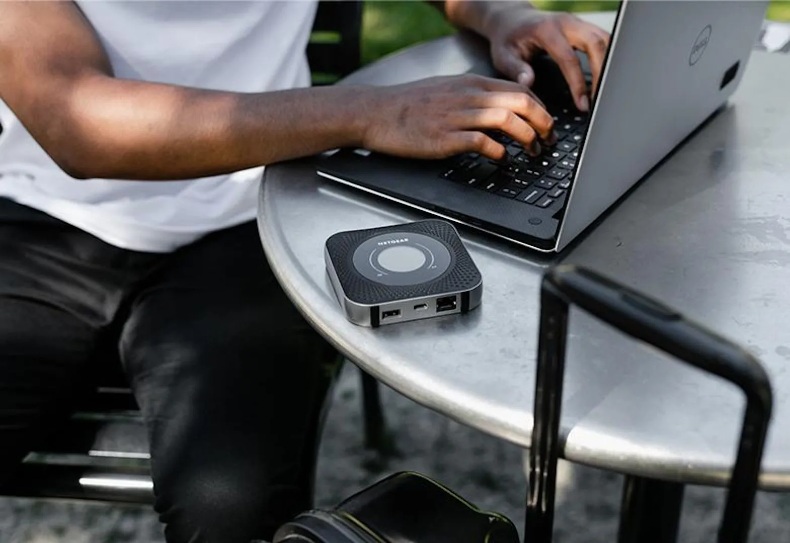 Router Wi-Fi di động Netgear Nighthawk M1 đặt trên bàn cà phê cùng laptop